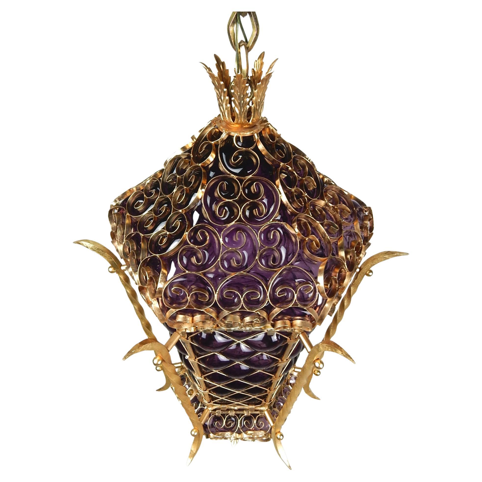 Gorgeous Bohemian caged purple glass in a gleaming gold metal swag pendant lamp, circa 1960s.
Takes a single standard light bulb in the 24 X 16 inch pendant.
Swags on a 15 foot custom chain or could be made into a ceiling pendant with ease.