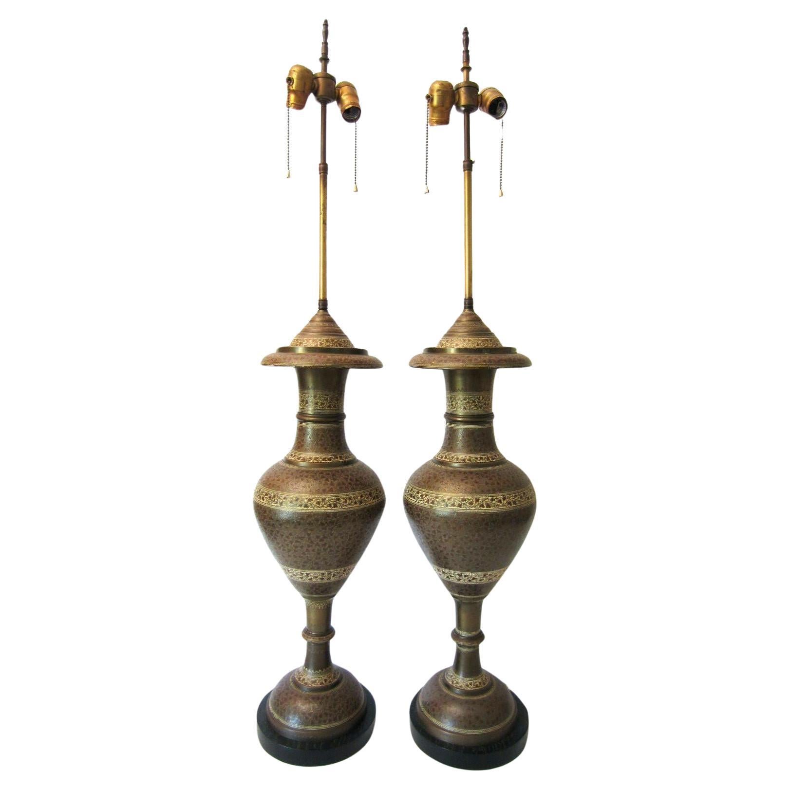 Tall pair of hand tooled brass urn table lamps from the Art Deco era.
Urns are mounted to an ebonized wooden base.
Double standard bulb sockets for each. Exceptional condition.

