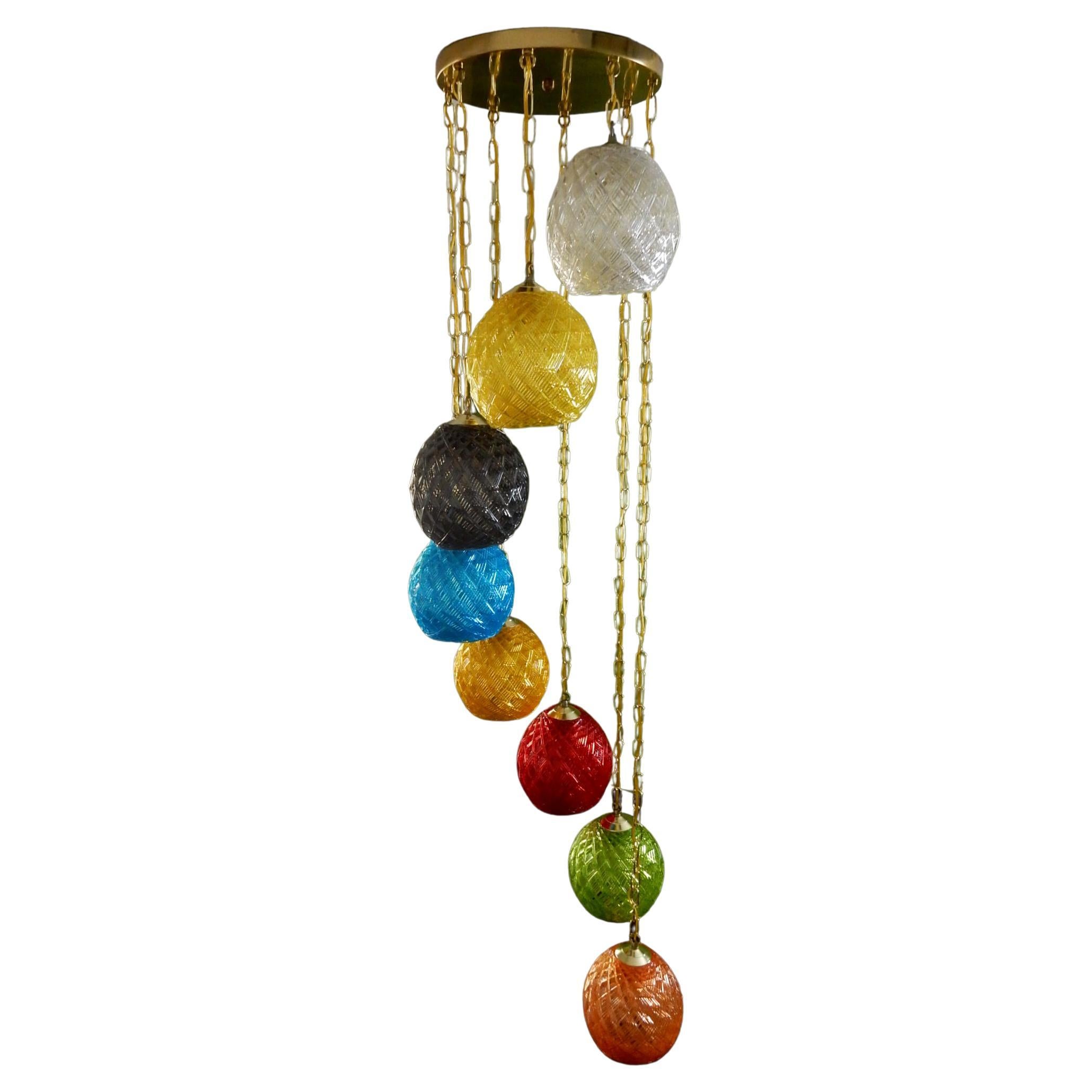 An amazing 8 shade cascading pendant chandelier from the 1960s.
Each colored shade of crystal Lucite in a geometric woven pattern.
Gleaming brass chain and large ceiling cap. Porcelain sockets.
This piece has been cleaned, rewired and is ready to