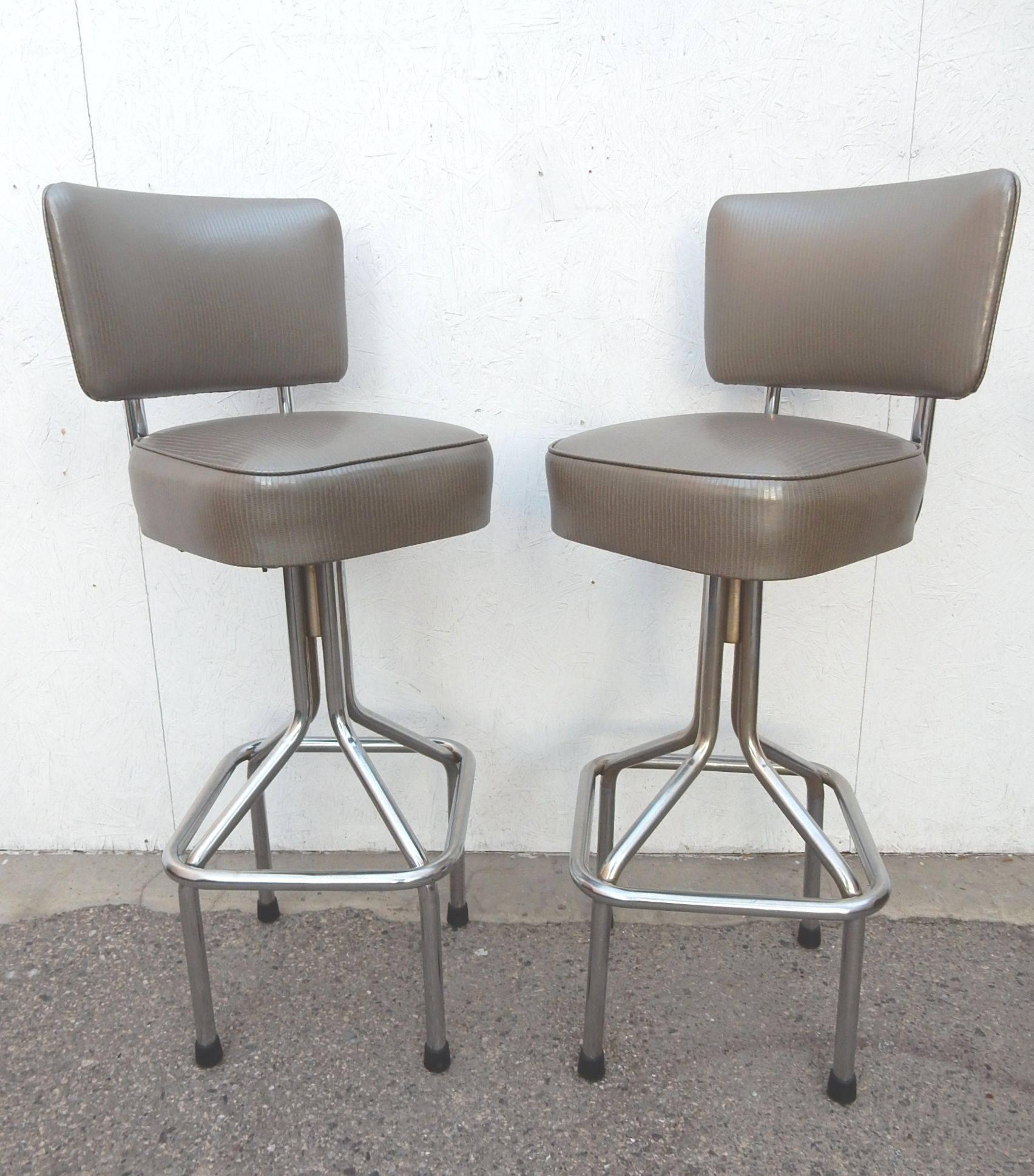 Classic set of quality bars stools from the 1950's. Made of think chrome plated steel tubes with needle bearing swivel mechanism. Freshly upholstered in a luxurious platinum faux snakeskin vinyl. Made in Los Angeles. 
Set of 4, all in excellent