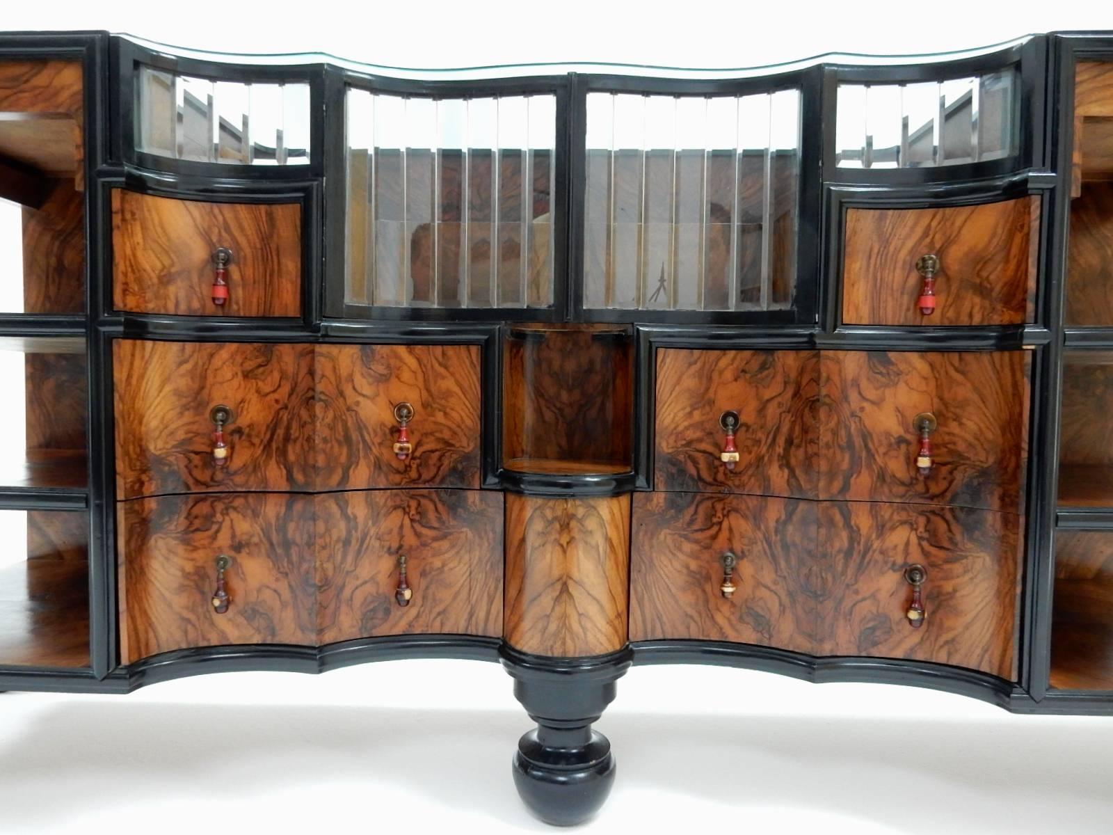 Exceptional dry bar sideboard cabinet, 1940's Italian.
A true work of art in every detail with all visual areas covered in gorgeous butterfly grain walnut veneer framed in ebonized molding.
Four sexy splayed legs with a huge center bun support leg