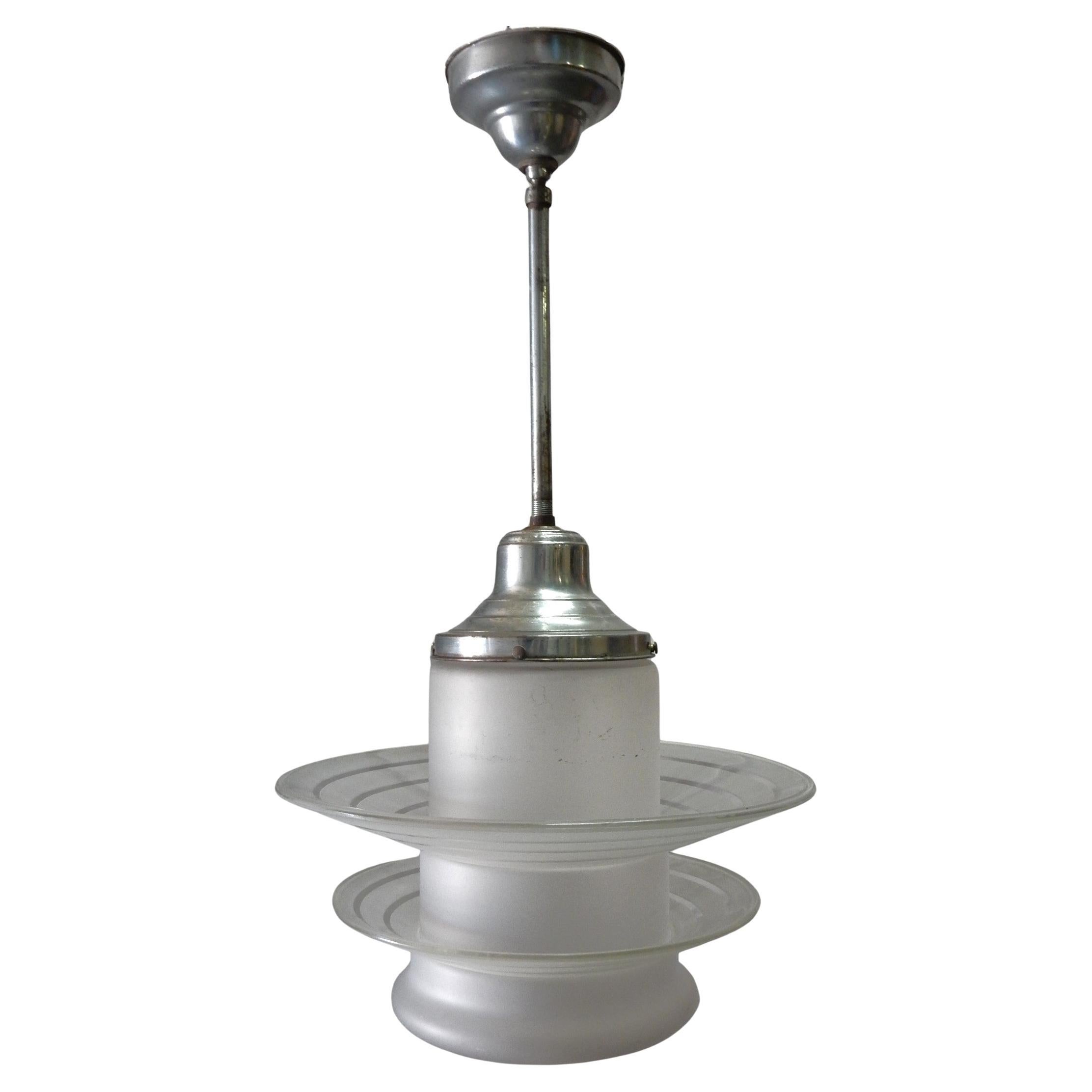 Incredible modernist design pendant lamp. 2 floating glass rings over a bullet shape glass globe pendant with aged steel fitter and ceiling cap. Circa early 1950's. 
Frosted main globe with alternating clear/frosted lines on the rings.
Large ring is