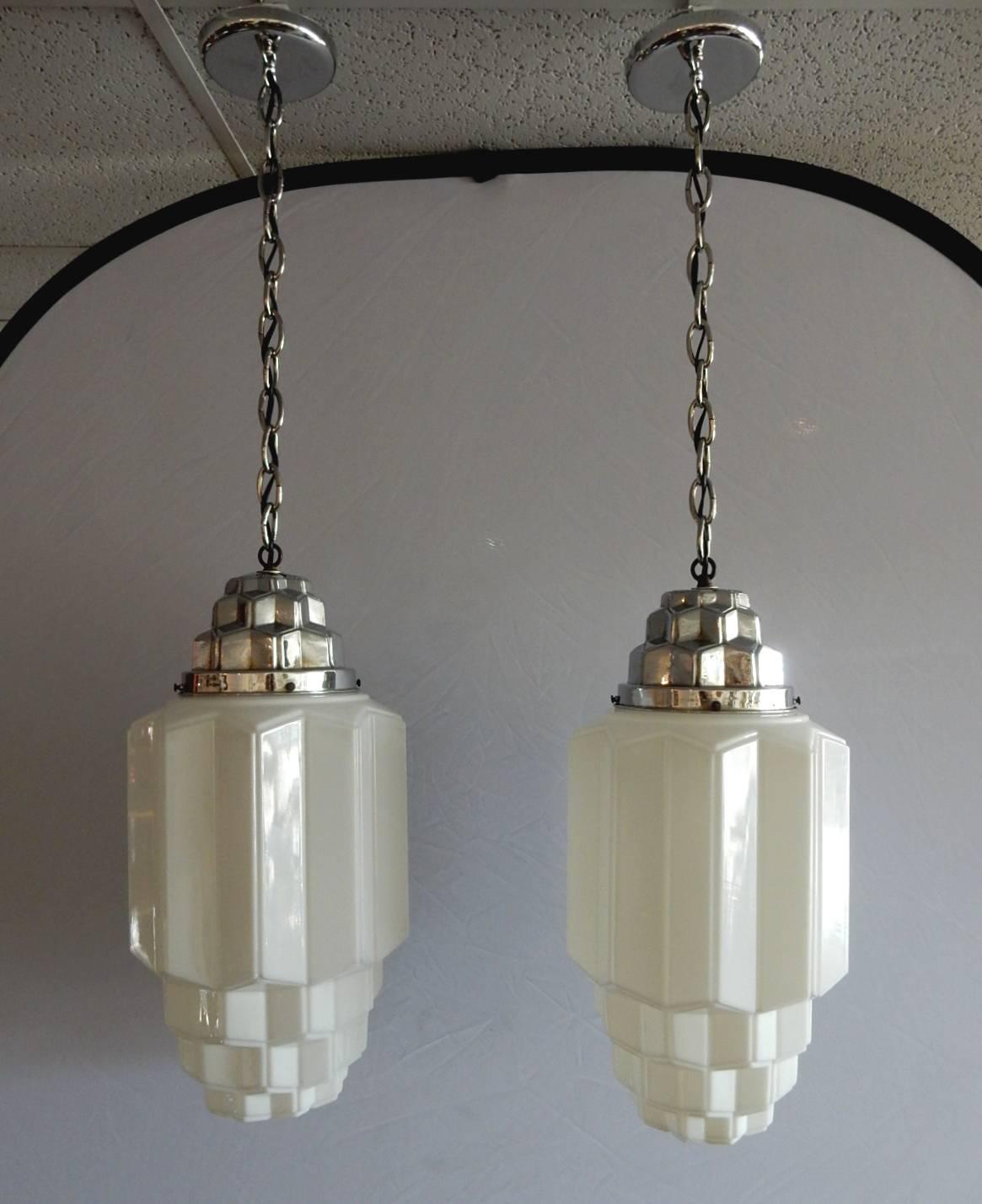 This set of commercial or theatre pendants made of thin hand formed milk glass with nickel-plated cap that identically mimics the cubist design, circa 1930s.
Each takes a single standard light bulb. New chrome chain, wiring and ceiling cap.