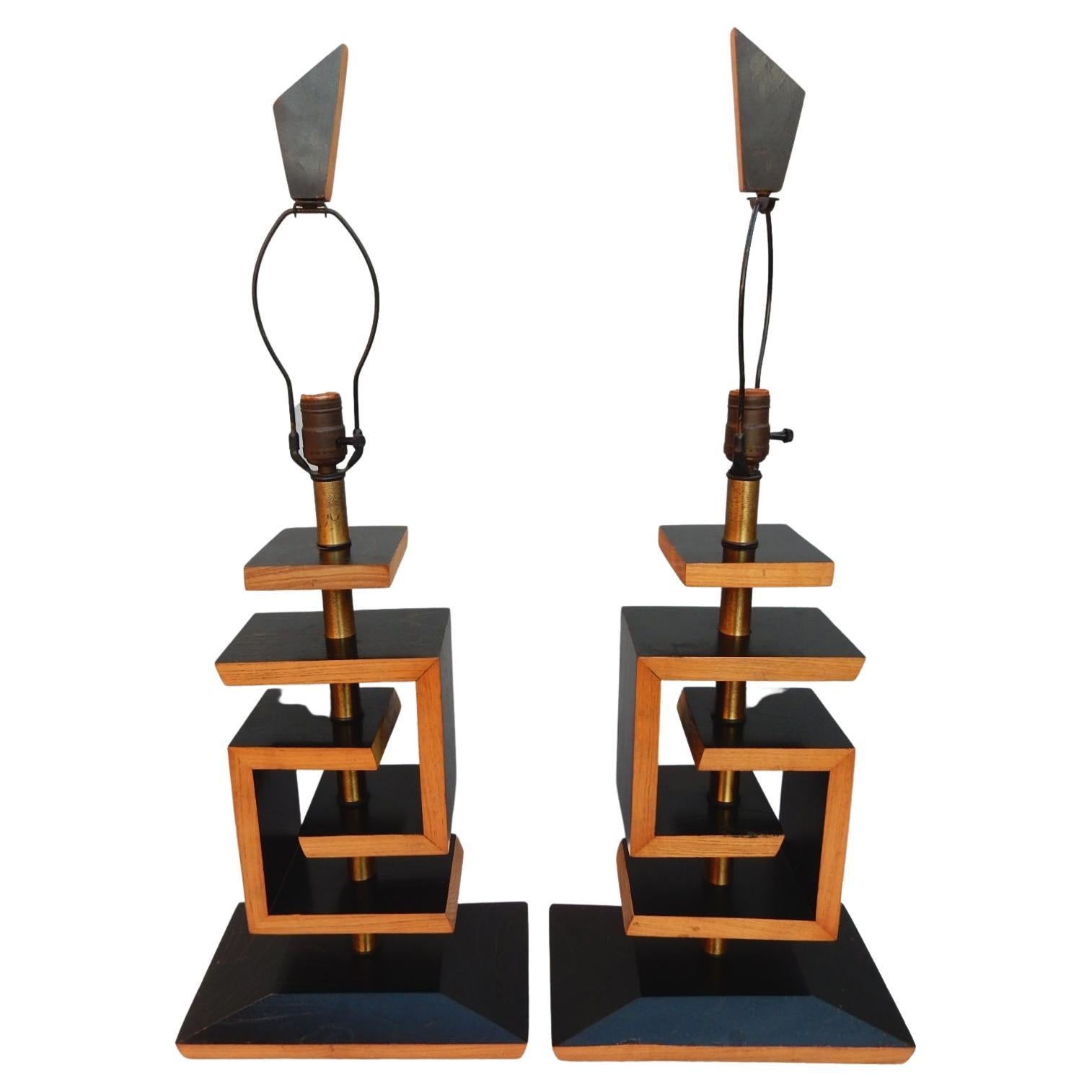A dramatic pair of sculpted geometric cerused oak table lamps designed in the style of James Mont, circa late 1940s.
Two-tone ebony and natural color. 
Included are the original two tone cloth shades and finials.