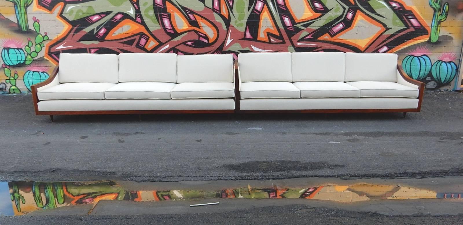 Fabulous newly upholstered(plus new premium foam)1960s sofa section with epic lines.
Two 7+ foot sections, one without inside arm.
Trimmed in walnut, front, sides and back. Ten tapered legs.
Can be arranged in an 