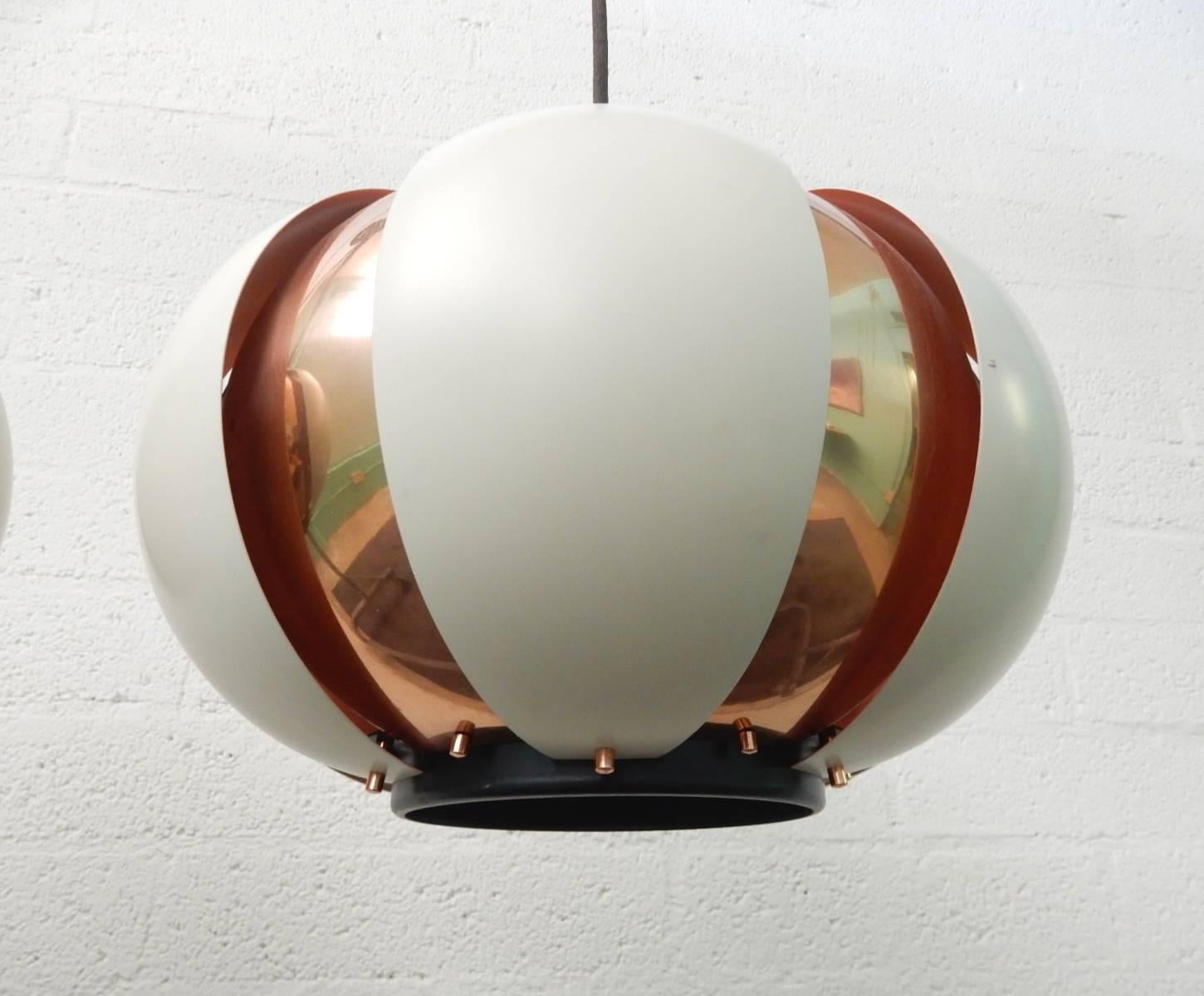 Pair of 1950s copper and white enamel louvered ball pendants lamps.
Both are complete and show just light wear/scratches. No dents.
Each takes a standard light bulb. Black cloth wiring is original but solid. No ceiling caps or mounting hardware