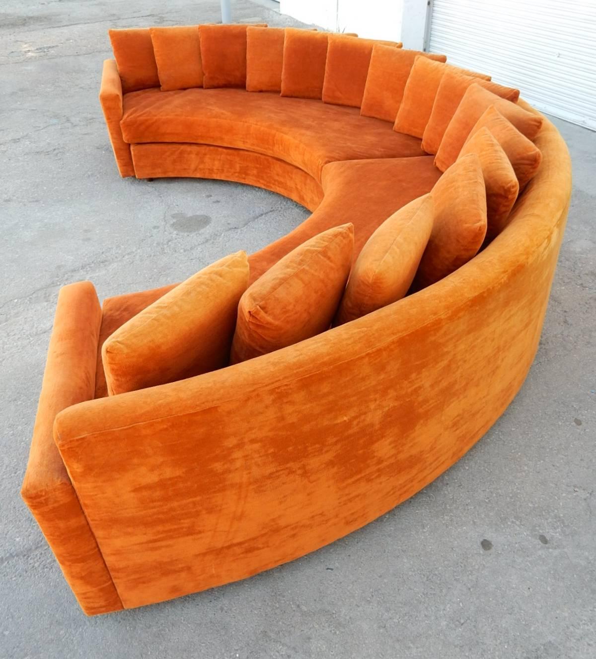Epic circa 1970s burnt orange velvet half round sofa by 21st Century Furniture for Barker Bros. 16 pillow back.
At 12 feet long across the arms this is a statement piece of grandest proportions.
Sets of round stubby wood legs.
It is in excellent