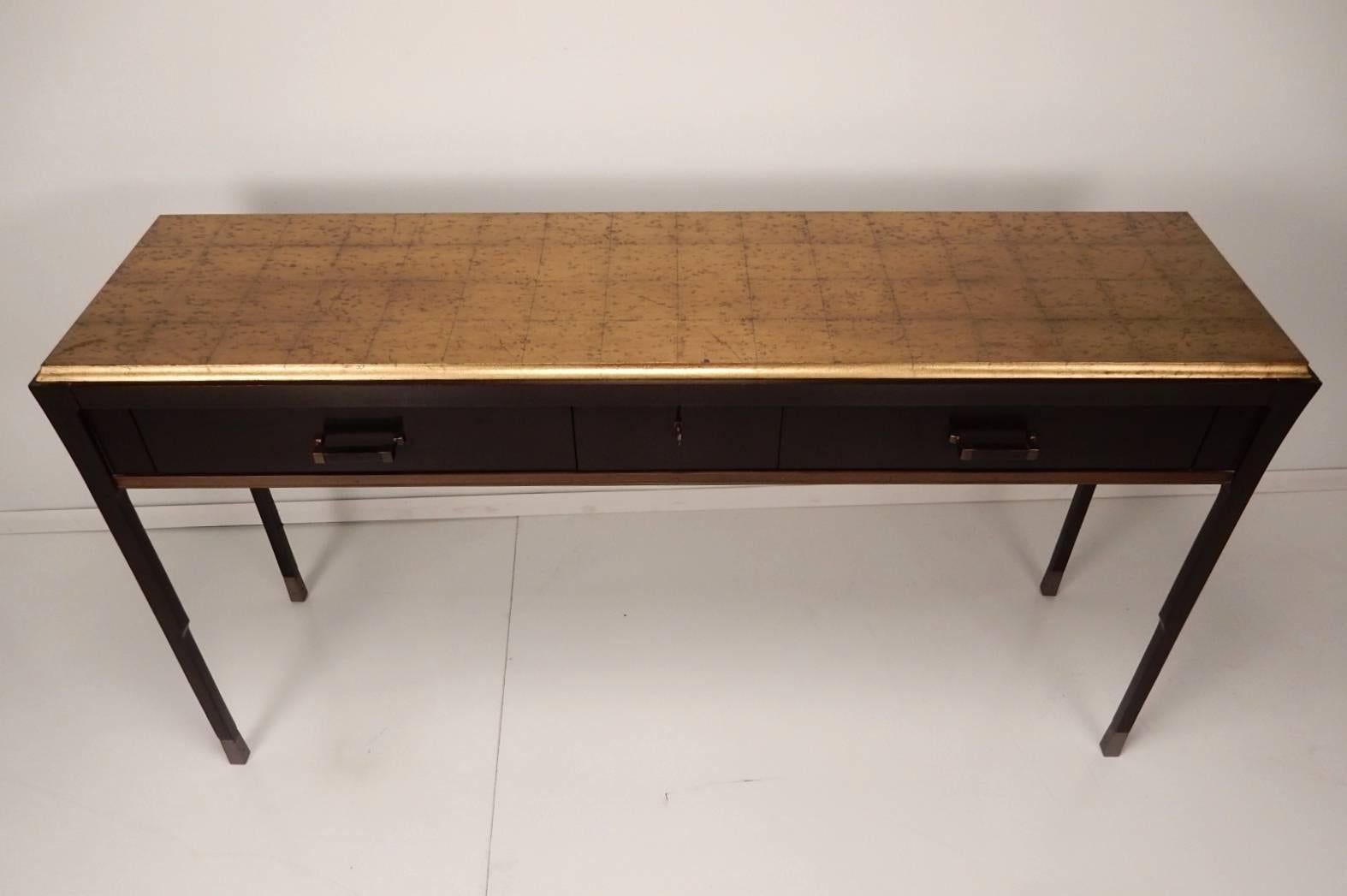 Dramatic rill hall table with gold rice finish top, two large drawers with a third lockable centre drawer (with keys). Four graceful taper legs capped in solid bronze sabots.
Designed by Bill Sofield for Baker Furniture.
Extraordinary well-crafted