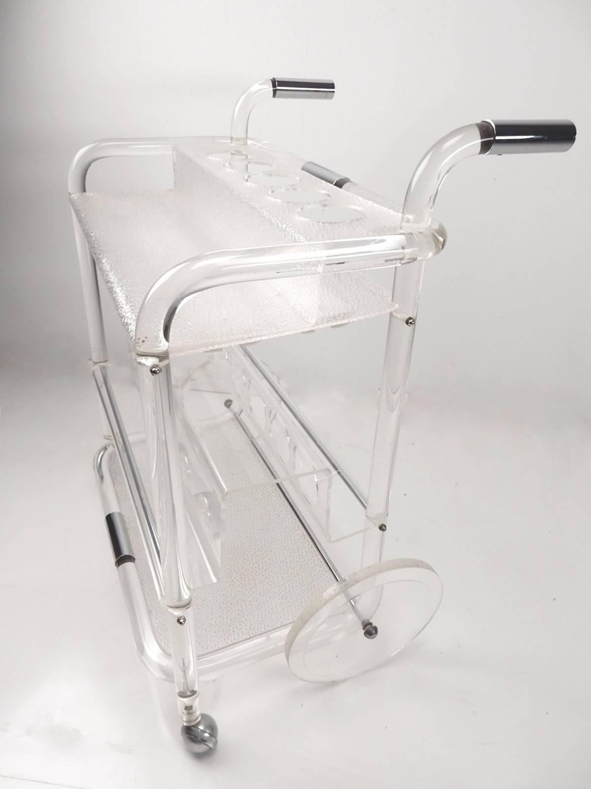 Unique 1960s rolling bar cart with a 1-1/2 inch solid Lucite rod capped with chrome steel handles.
Centre shelf holds six bottles. Bottom and top shelves have an ice finish with lots of room for glasses and four more decanters on top.
Large Lucite