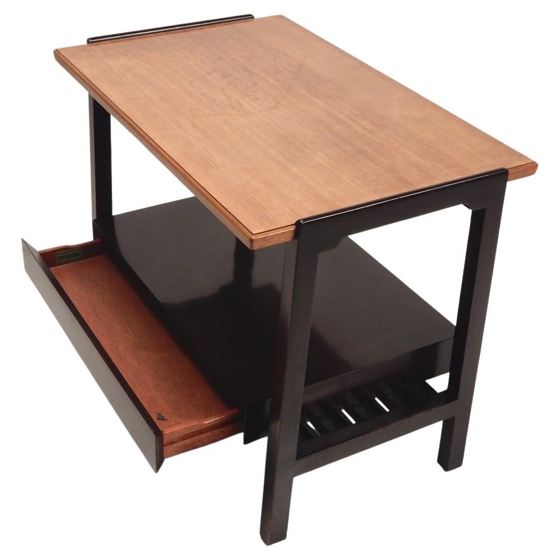 Table d'appoint bicolore conçue par Edward Wormley pour Dunbar Furniture, vers la fin des années 1940.
Plateau en acajou clair avec cadre inférieur ébénisé et un seul tiroir en caisson furtif sur une étagère inférieure en lattes.
État légèrement