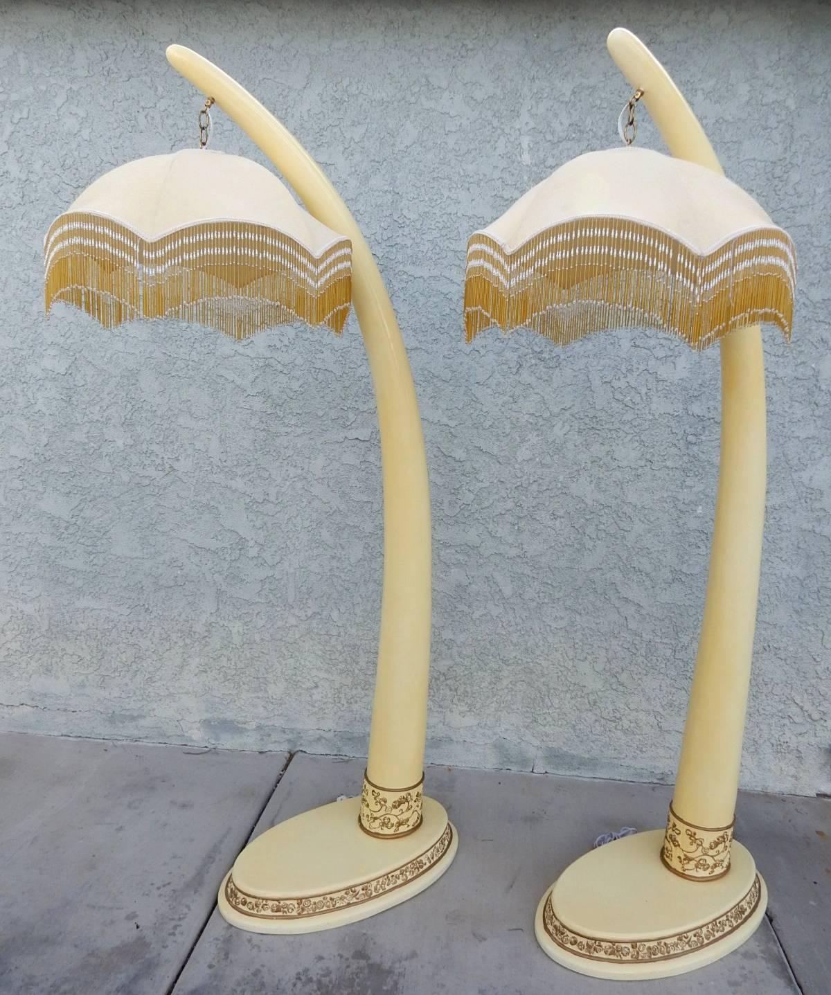 Monumental pair of faux elephant tusk floor lamps with glass beaded fringe shades.
Made of a composite plastic, circa 1960s in the style of the Art Deco era.
Not signed or marked.
 