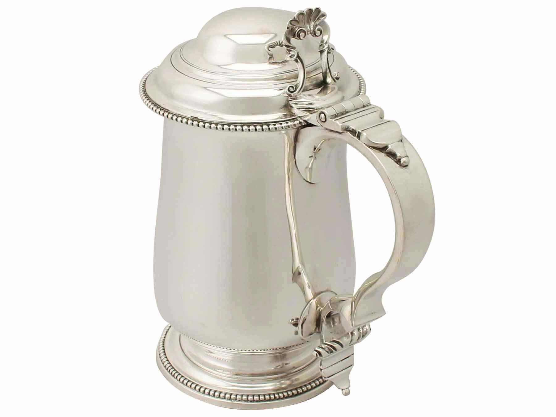 This exceptional antique George III sterling silver quart tankard has a plain baluster form onto a spreading circular foot.

The plain body of this Georgian tankard is embellished with an impressive bright cut engraved oval cartouche encompassed