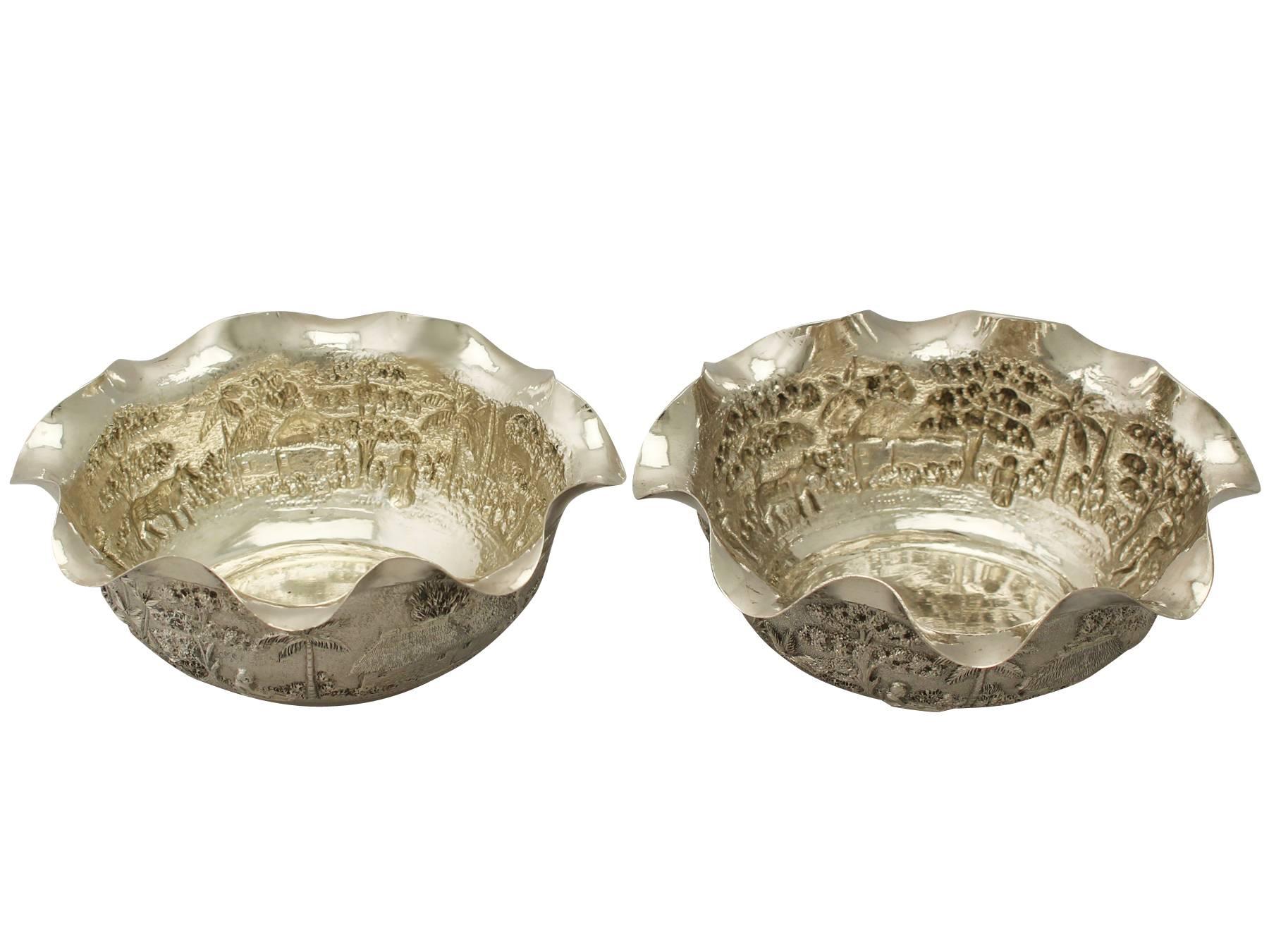 These fine antique Indian silver bowls have an oval rounded form.

The surface of each bowl is embellished with an impressive embossed and chased decorated scene depicting figures maintaining a village from their surroundings and lounging upon the