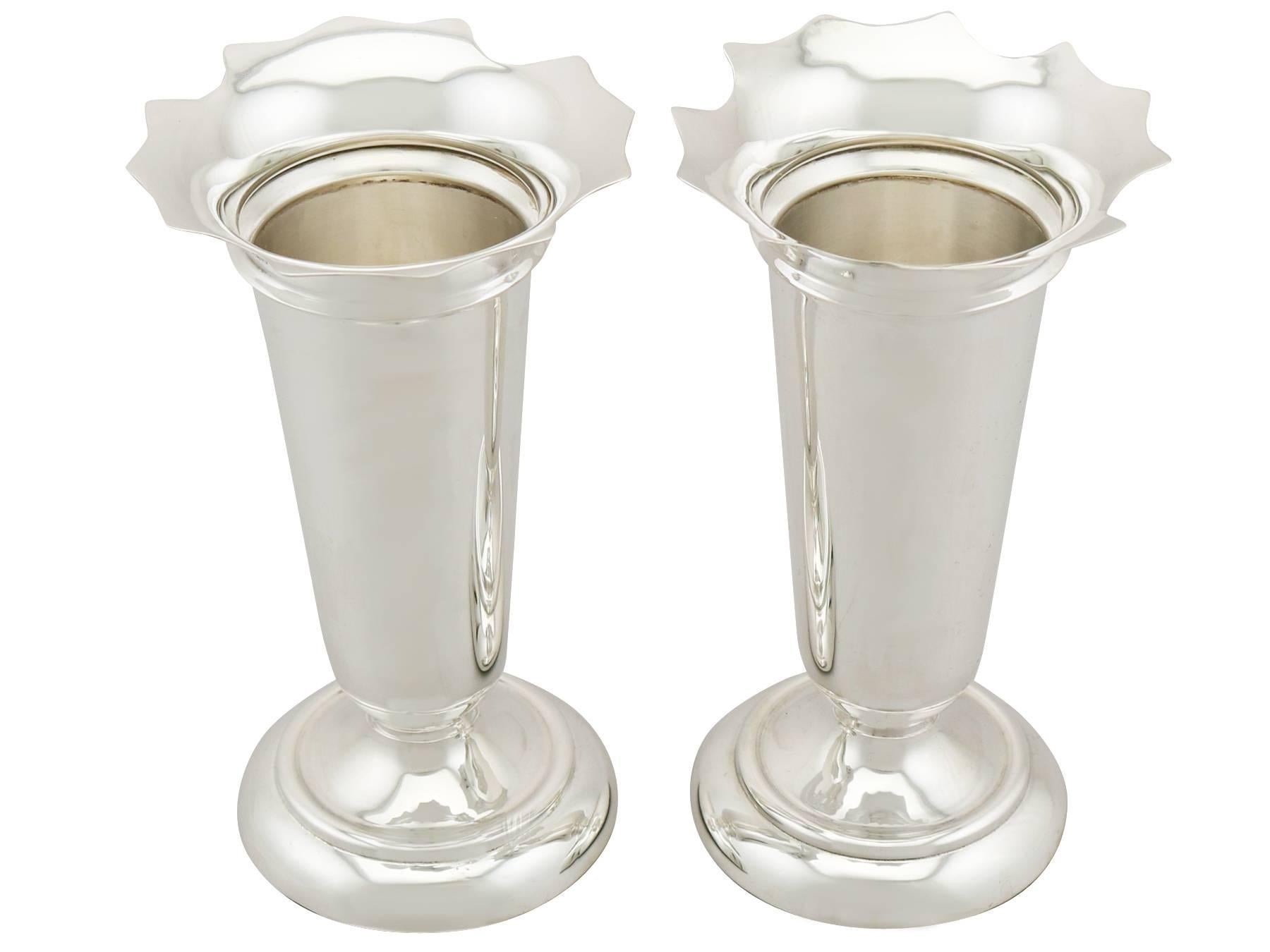 A fine pair of antique George V English sterling silver vases; an addition to our ornamental silverware collection.

These impressive antique sterling silver vases have a tapering cylindrical form with a flared incurved, shaped rim.

The surface