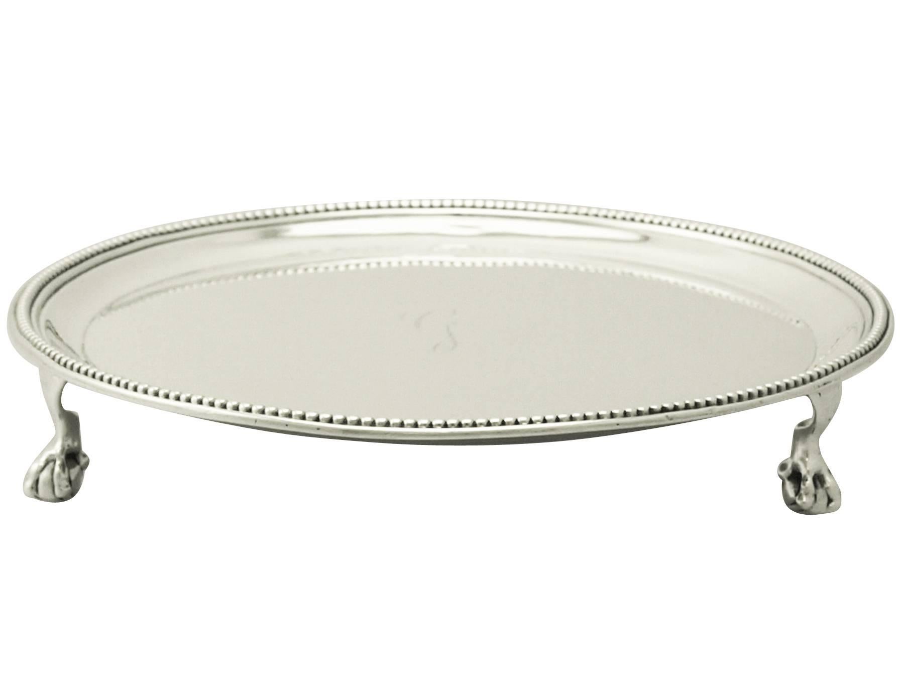 A fine and impressive antique Georgian English sterling silver waiter; an addition to our dining silverware collection.

This fine antique George III sterling silver waiter has a plain circular form.

The surface of this waiter is embellished