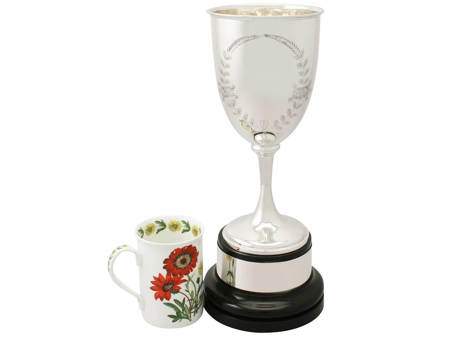 A fine and impressive antique George V English sterling silver presentation cup; part of our presentation silverware collection.

This fine antique George V sterling silver presentation cup has a plain circular bell shaped form supported by a