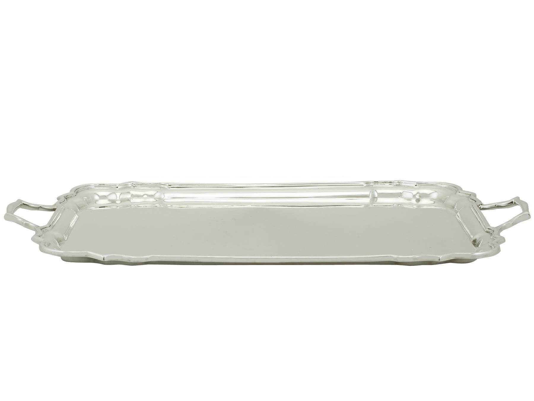 An exceptional, fine and impressive vintage George VI English sterling silver drinks tray; an addition to silver tea ware collection.

This exceptional vintage George VI sterling silver drinks tray has a plain rectangular form with incurved shaped