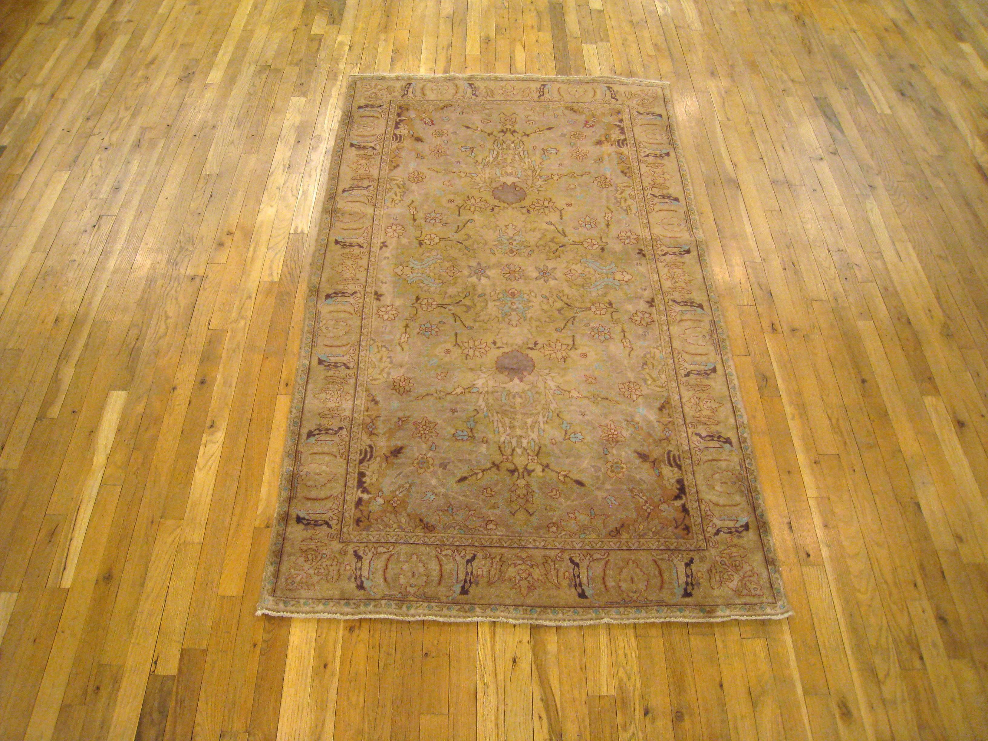 An antique Indian Agra oriental rug, size 7' x 4', circa 1900.  This fine hand-woven wool carpet features a simple yet elegant floral design at the center of the softly hued central field, with a complementary stiff leaf outer border.  Short wool