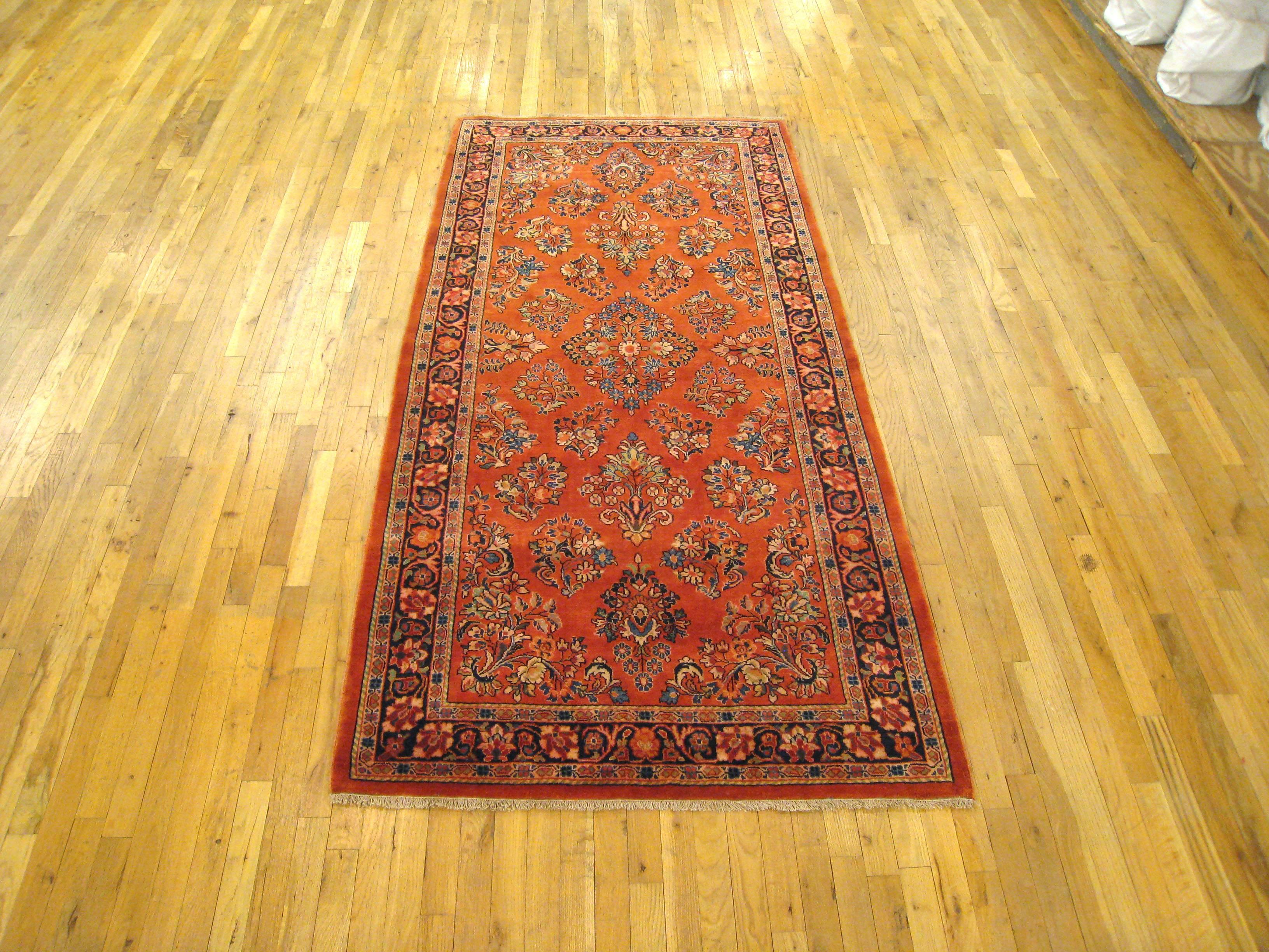A vintage Persian Sarouk oriental rug, size 7'9 H x 3'9 W, circa 1930.  This lovely hand-woven wool rug features an elegant floral design on a traditional red field with a navy blue border.  This piece is an exemplary classical Persian rug, in