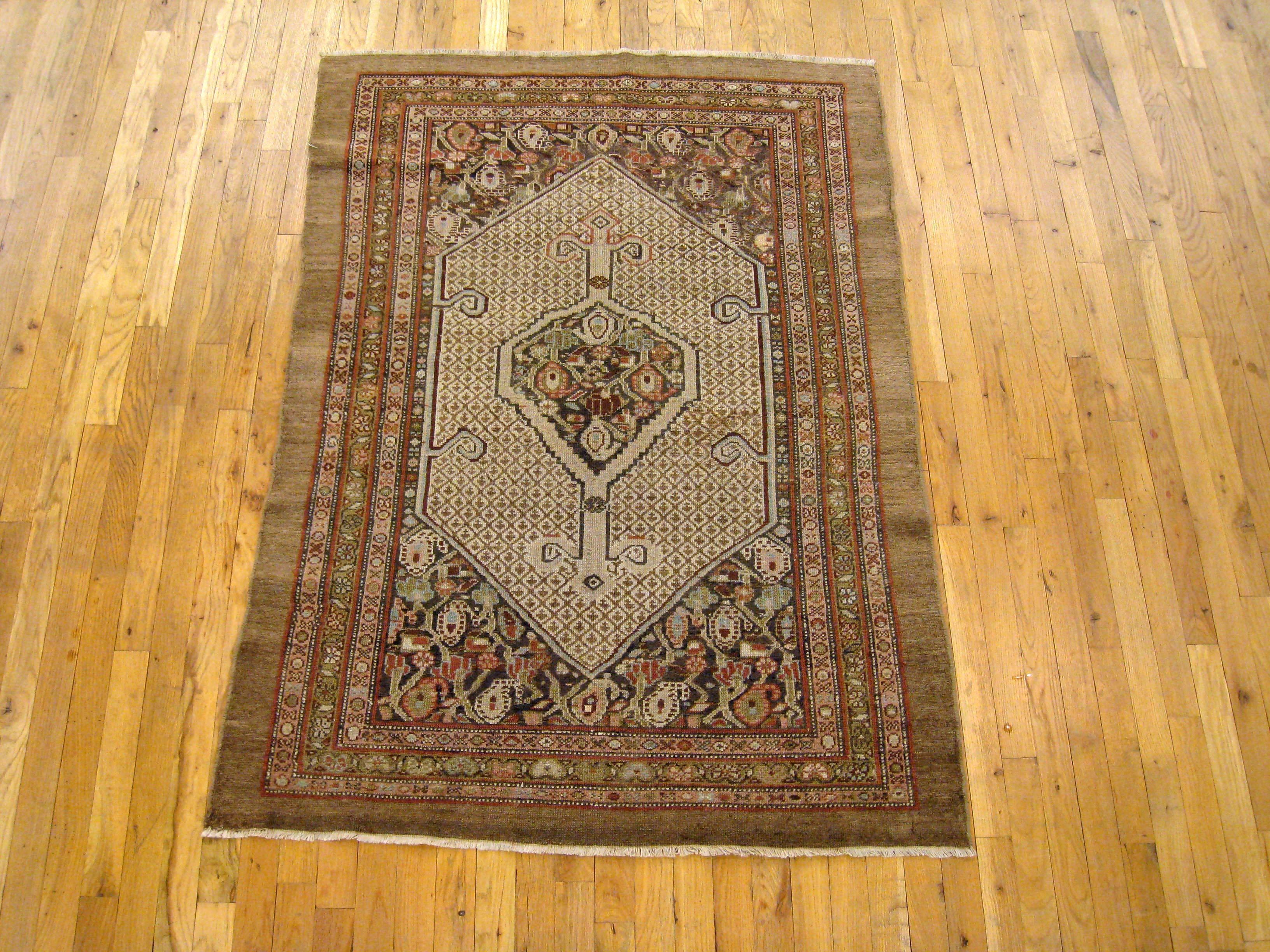 An antique Persian Hamadan camel hair oriental rug, circa 1910, size 5'2 x 3'9. This delightful small carpet features a central cartouche with a gul medallion, embedded within a field of small diamond elements, and complemented by end designs of