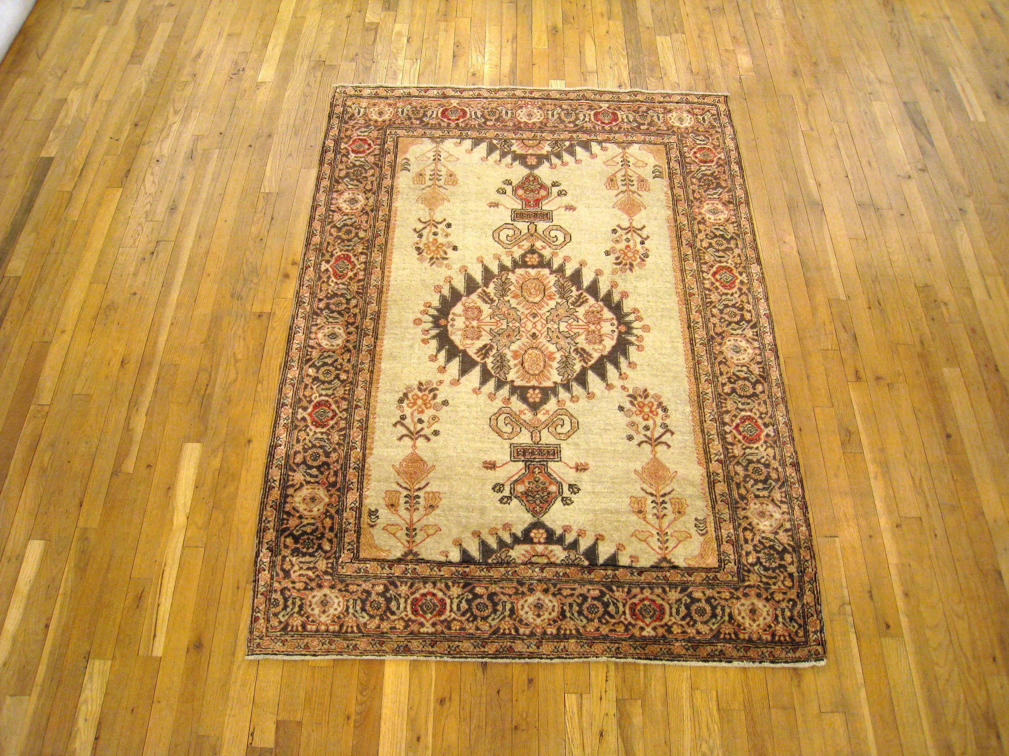A small antique Persian Tabriz decorative rug, size 6'5 H x 4'6 W. This handsome hand-woven oriental carpet features a central lozenge medallion on a softly hued ivory field, with earth tones a subtle colors throughout. Wool pile with a short nap