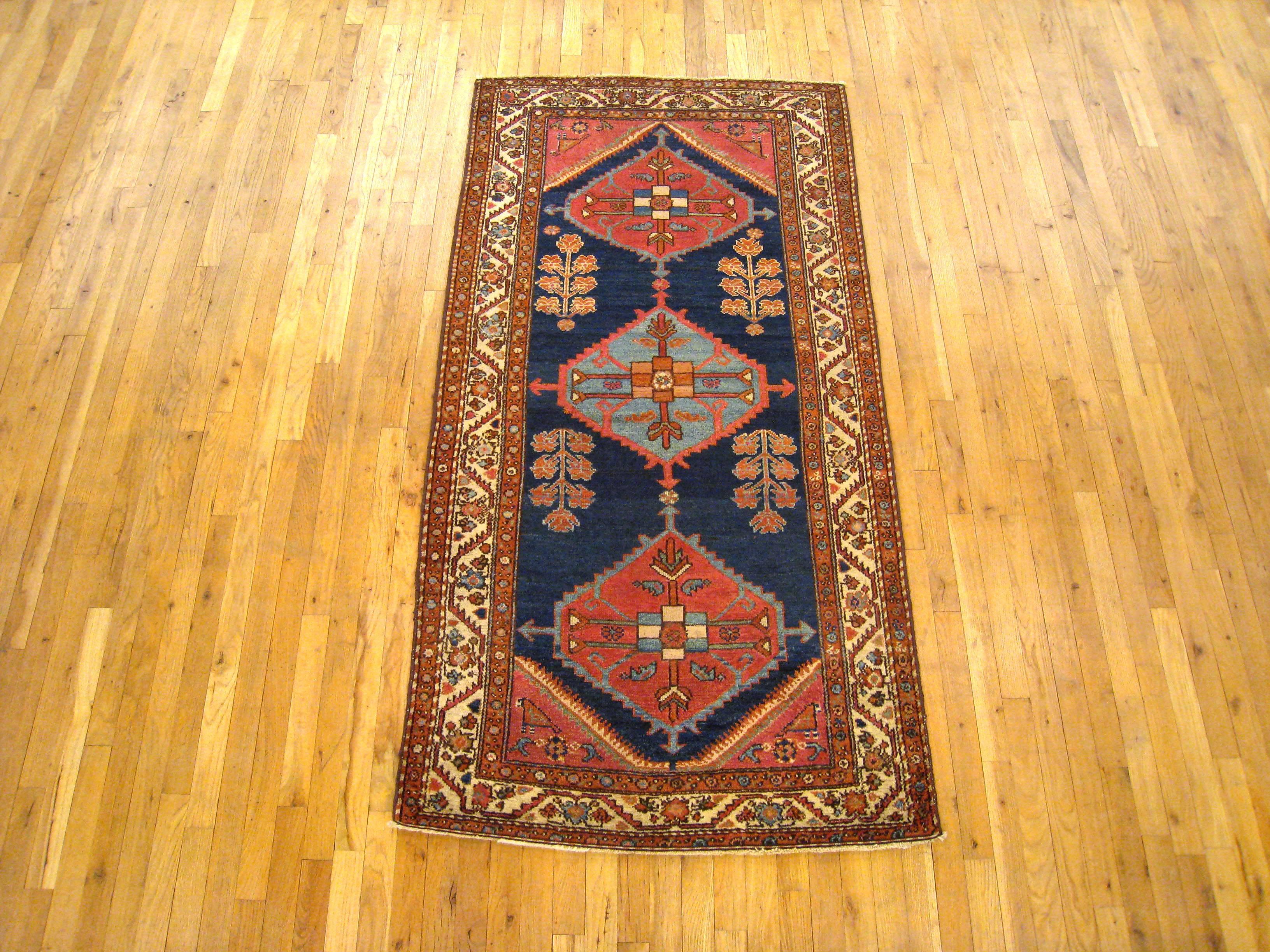 An antique Persian Hamadan oriental rug, circa 1910. Size: 6'6 x 3'4. This decorative hand knotted antique carpet features a delightful design with three prominent medallions in the central area, covering an otherwise sparse blue field, with simple