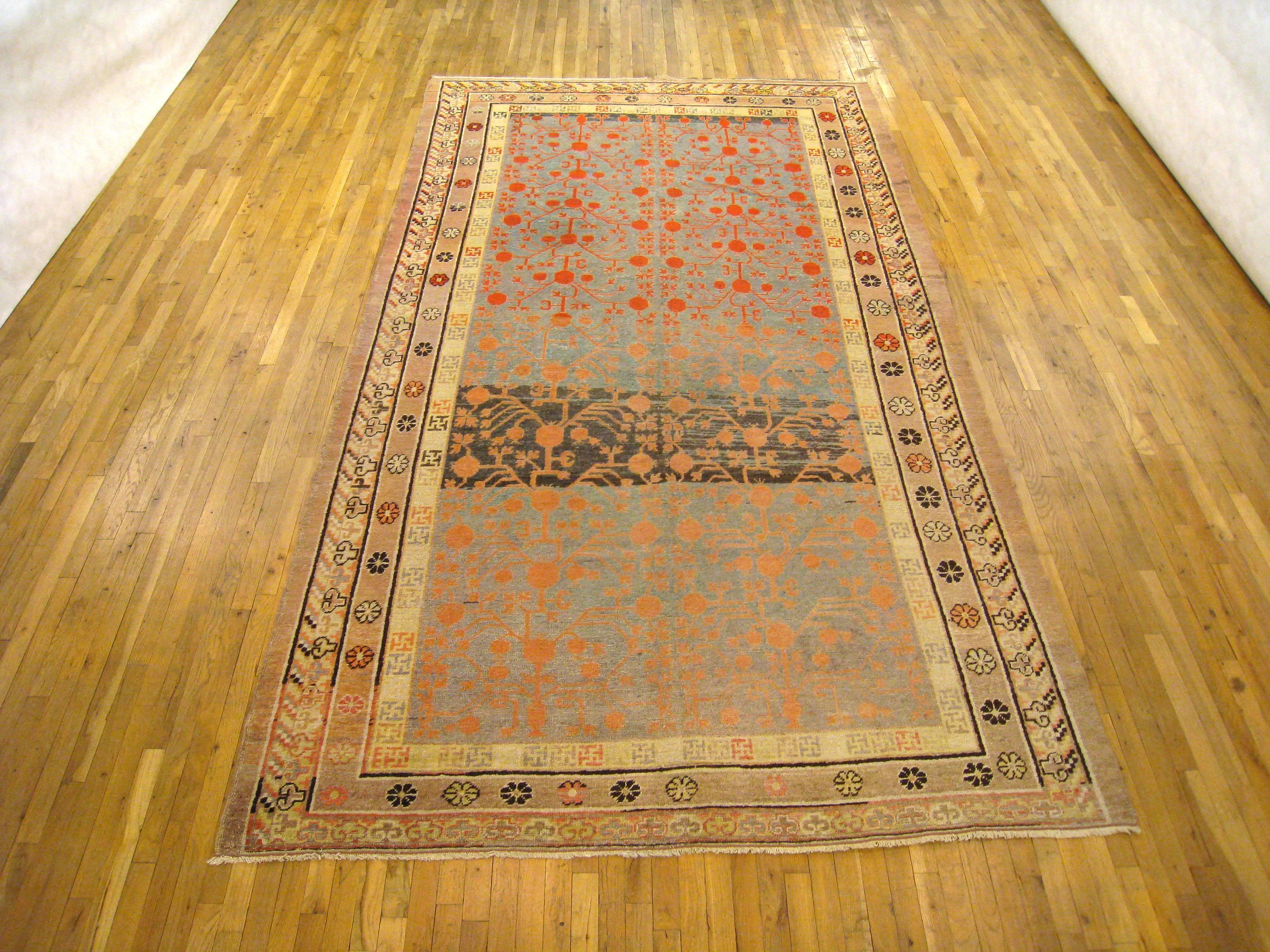 An antique Khotan oriental carpet, size 12'8 x 6'10, circa 1890. This handsome antique decorative rug features a stylized repeating design on a light blue background, with different shades of light blue from one end to another. This color variation,