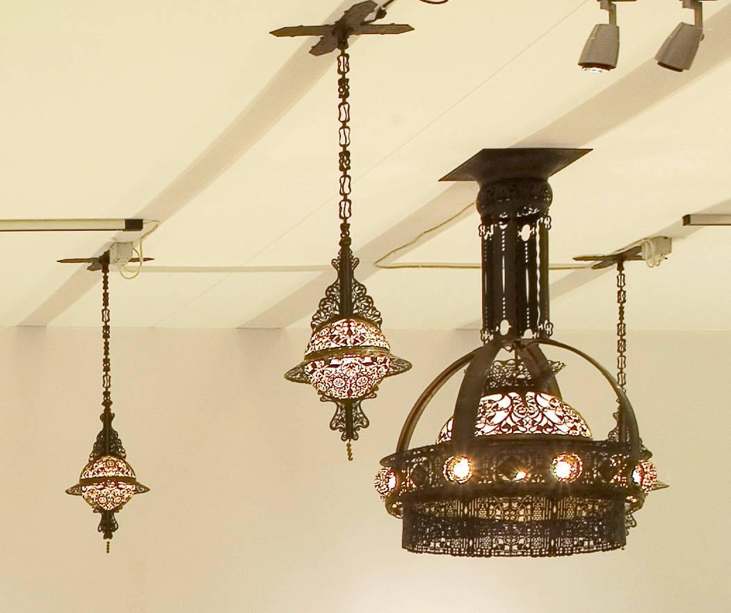 Five hanging lamps, the big one in the middle of the ceiling the four smaller ones in each corner of the ceiling. Bronzed copper with a hand cut floral decoration.
The big one has a shade of silk with a floral batik decoration and the glass dome