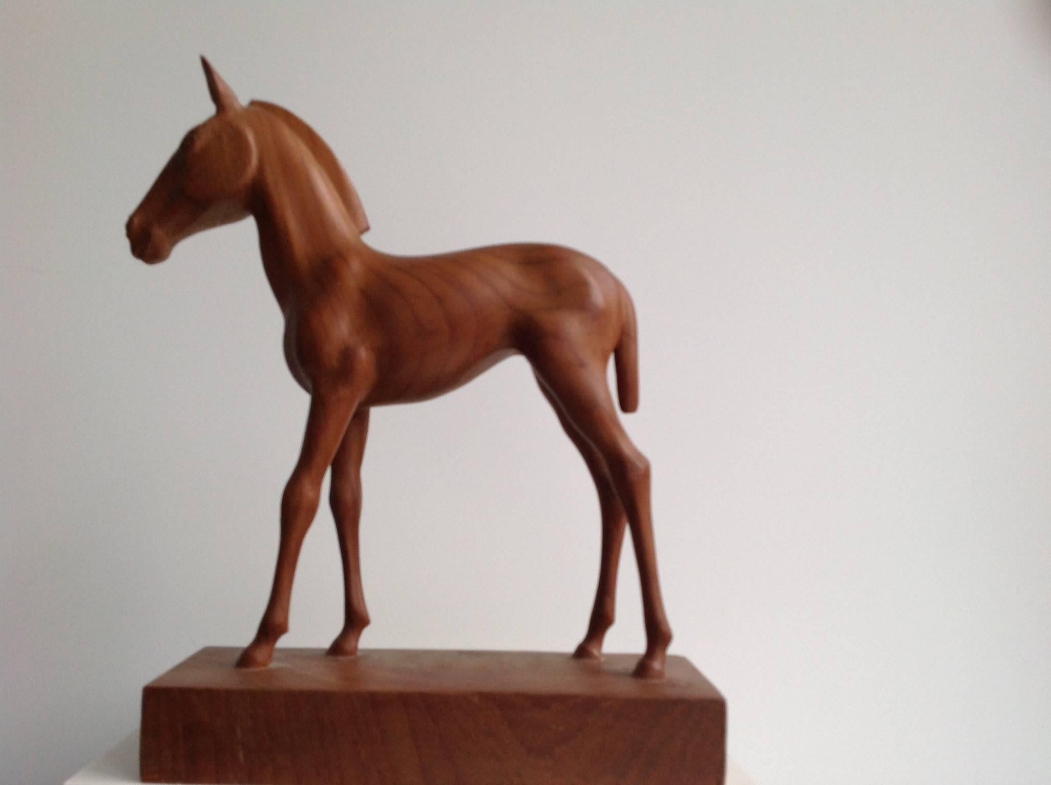 A pretty sculpture of a foal made in teak, signed and dated.