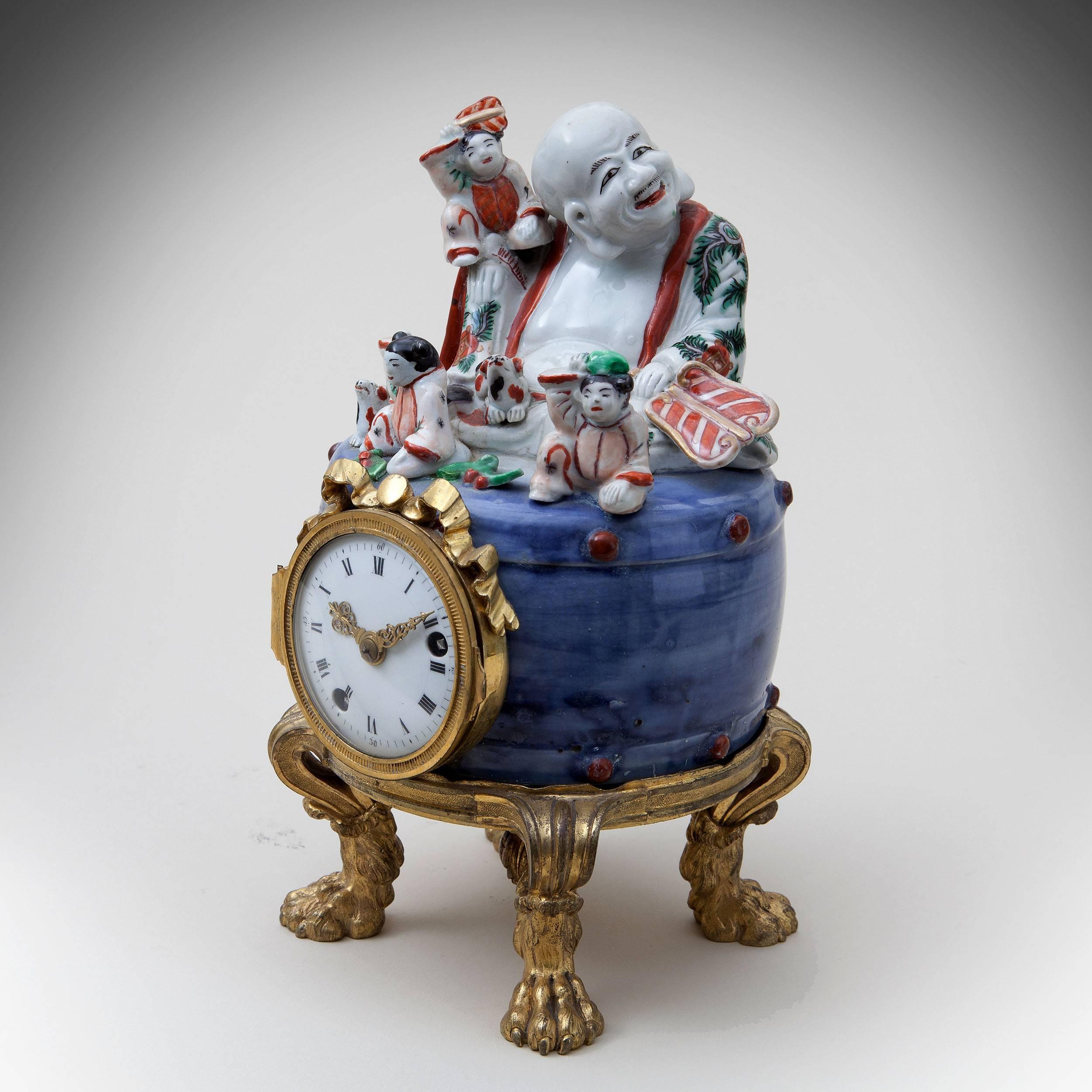 A fine French mantel clock by Louis Montjoye, Paris. The richly chased and gilt ormolu mounts as hairy paw feet supporting a Arita figure of a Hotei seated on a drum with puppies and children, decorated in polychrome enamels. 

Measures: Height