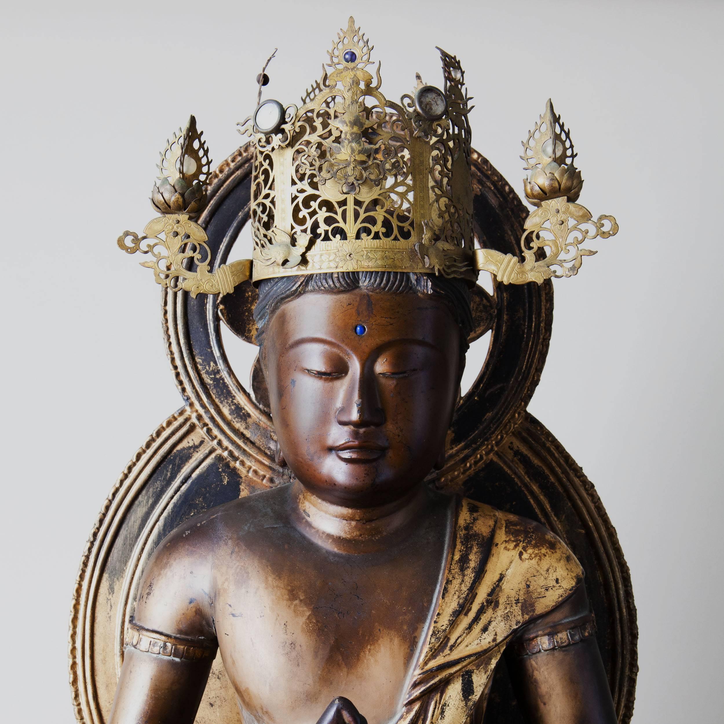 A fine carved wooden and gilt figure of a Japanese Buddha, Dainichi Nyorai, the surface with lacquer and gilt work, the Buddha wearing a pierced jewelled crown and seated cross-legged with fine drapery, supported on a carved lotus flower and raised