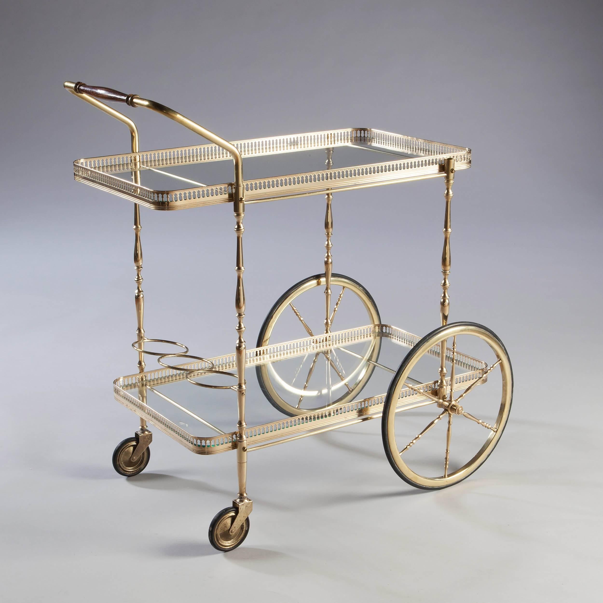 A fine large wheeled polished brass bar cart, the polished brass trays with glass bottoms raised on turned solid brass legs, they trolley with its original turned wooded handle.