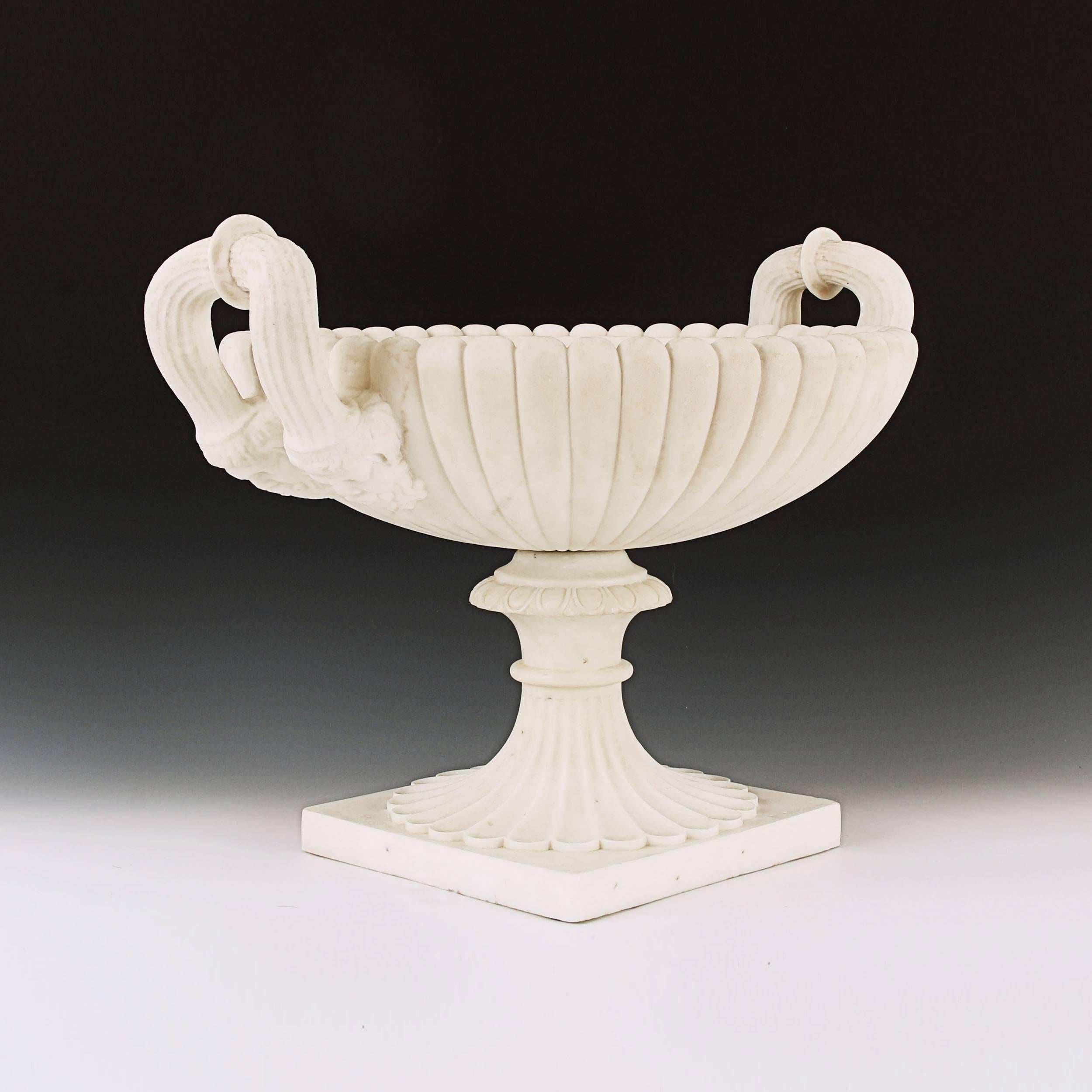 This elegant and refined masterpiece, carved from beautiful white marble, draws inspiration from both the ancient Greek Kylix form & Roman Neoclassicism. Carved from two solid sections. The upper gadrooned crater, each side with generously