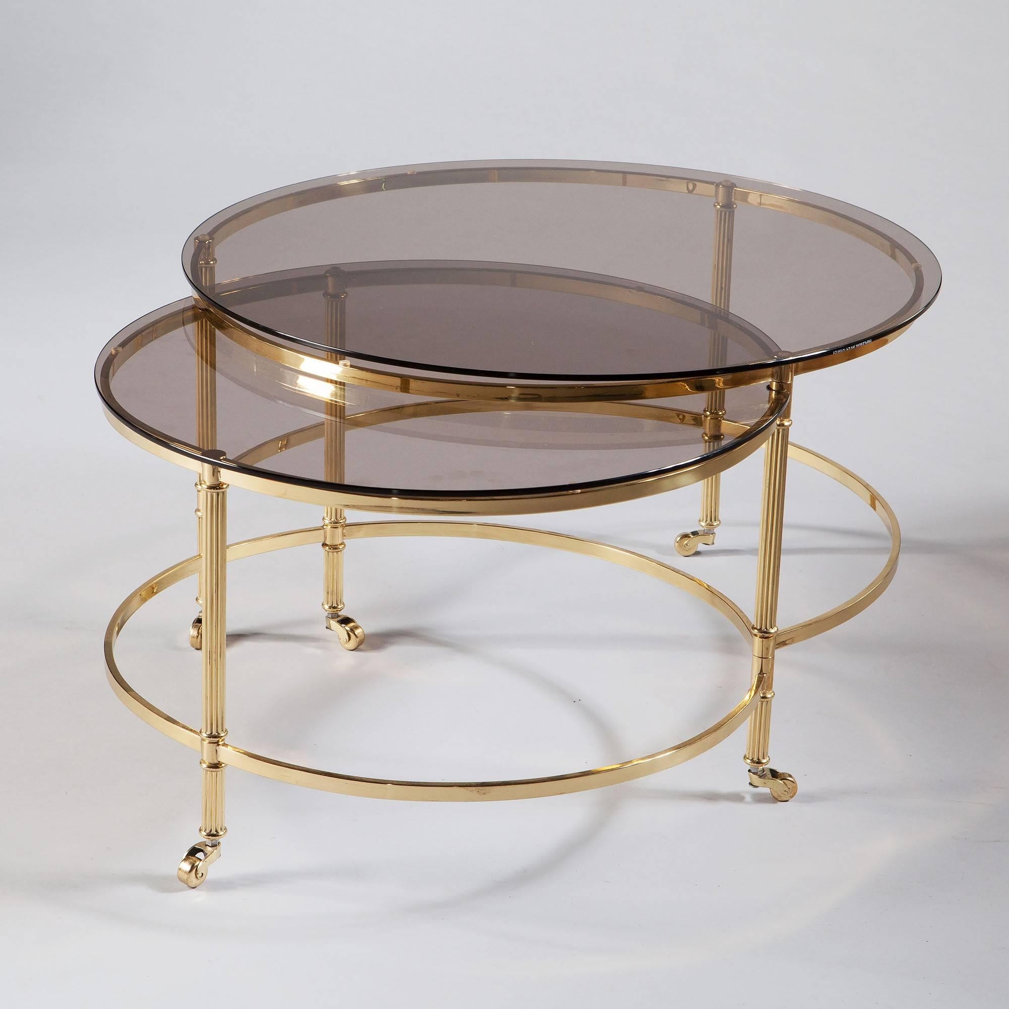 An unusual patent Mid-Century circular lacquered brass occasional table with reeded columns terminating in brass casters. The table disguises within it a second tier that can roll out to form a separate though joined table,

France,