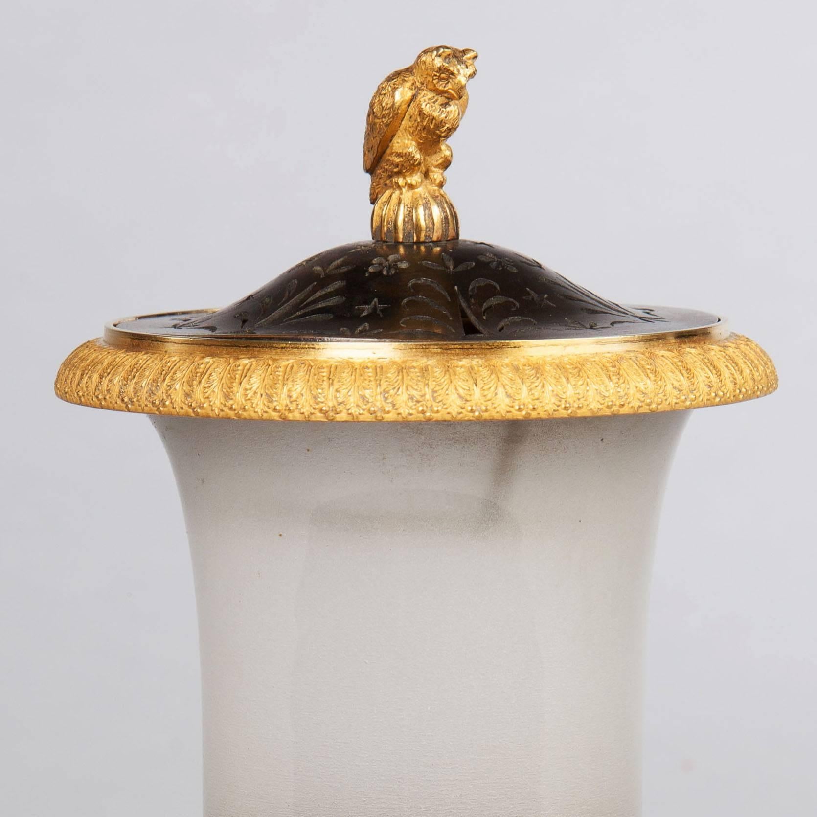 An Empire bronze and gilt opaline night light.

A rare and unusual Empire night light or incense burner. The pierced bronze lid is surmounted by a gilt bronze owl. The campana form of the body is frosted opaline and supported on a gilt and bronze