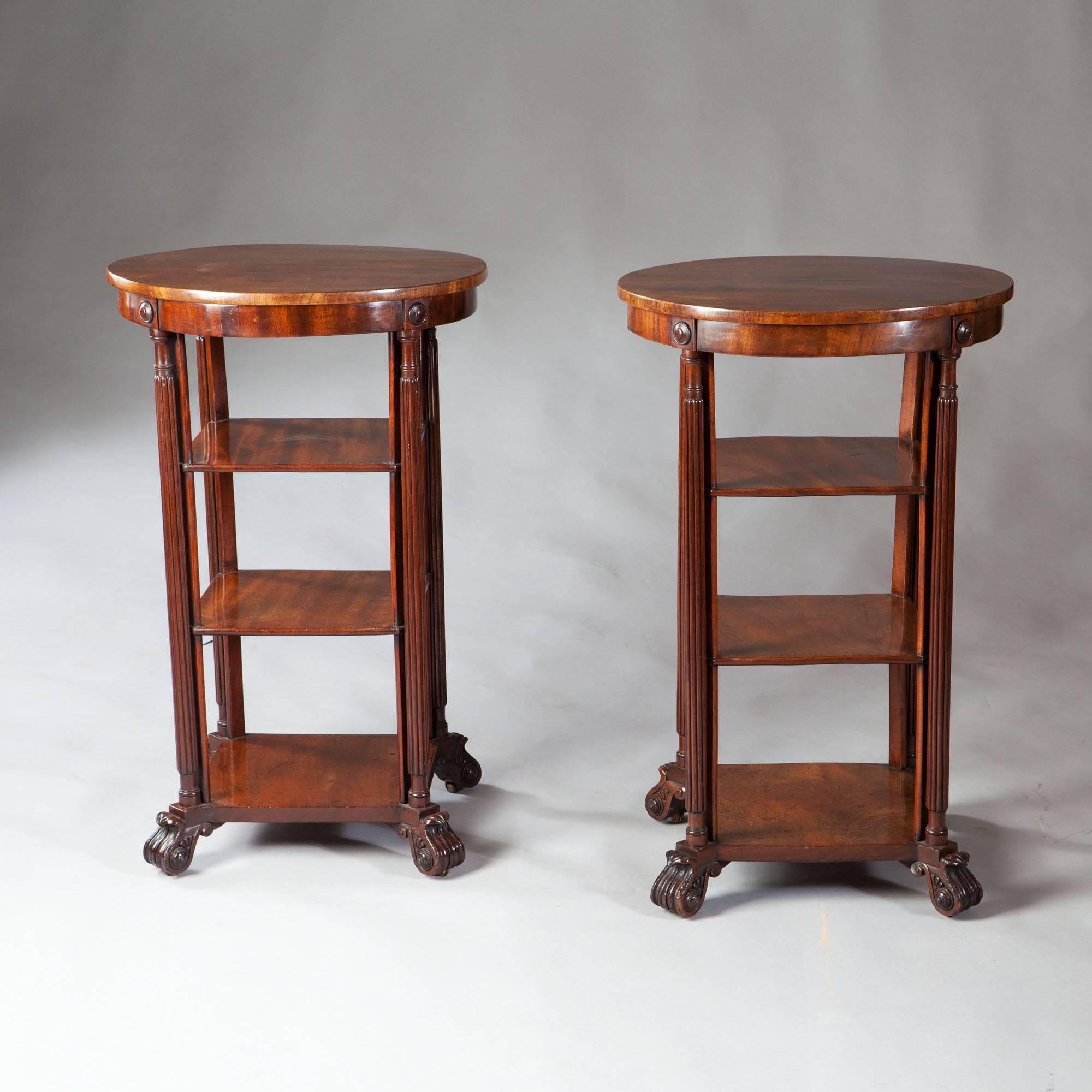 A pair of William IV mahogany three-tier end tables, the circular tops raised on fluted legs supporting two shelves and raised on bracket feet with carved foliate detail.

Attributed to Gillows.
Measures:
Height 30 1/4in.
Diameter of top 19