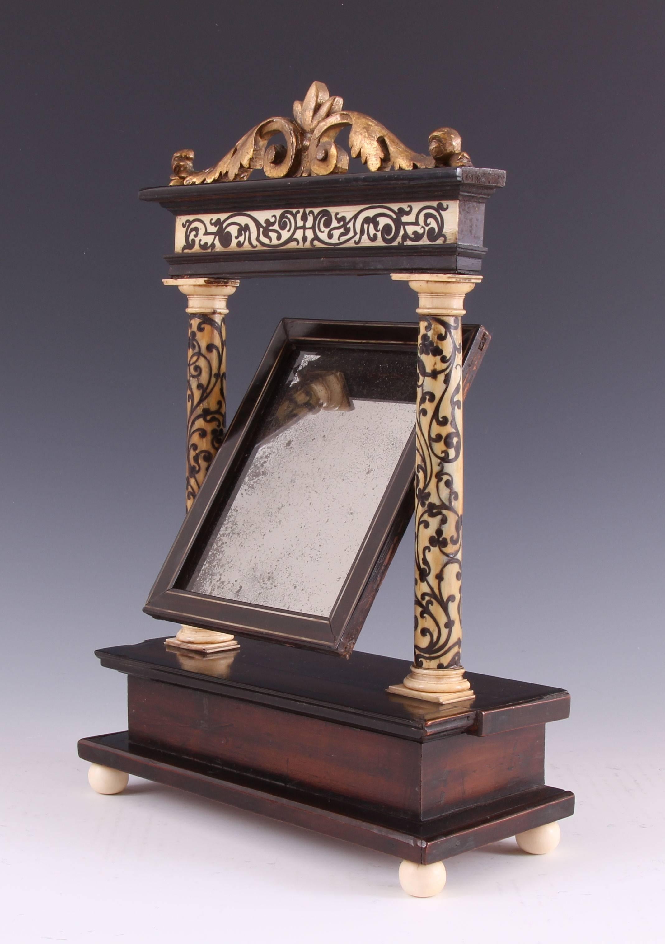 Rare 17th century Neapolitan ebony and bone inlaid walnut giltwood mounted toilet mirror. The rarity of this small piece cannot be overstated. The veneered inlaid columns are superb and a delight to behold, as is the inlaid frieze. The giltwood leaf