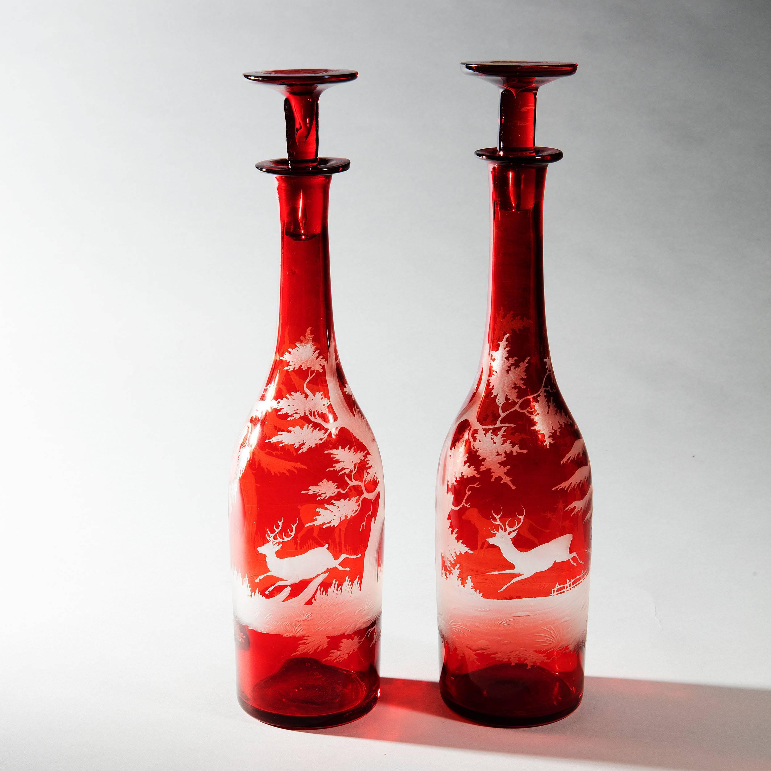 Wonderful pair of a ruby red bohemian engraved glass decanter with wheel engraved scenes of a deer hunt.