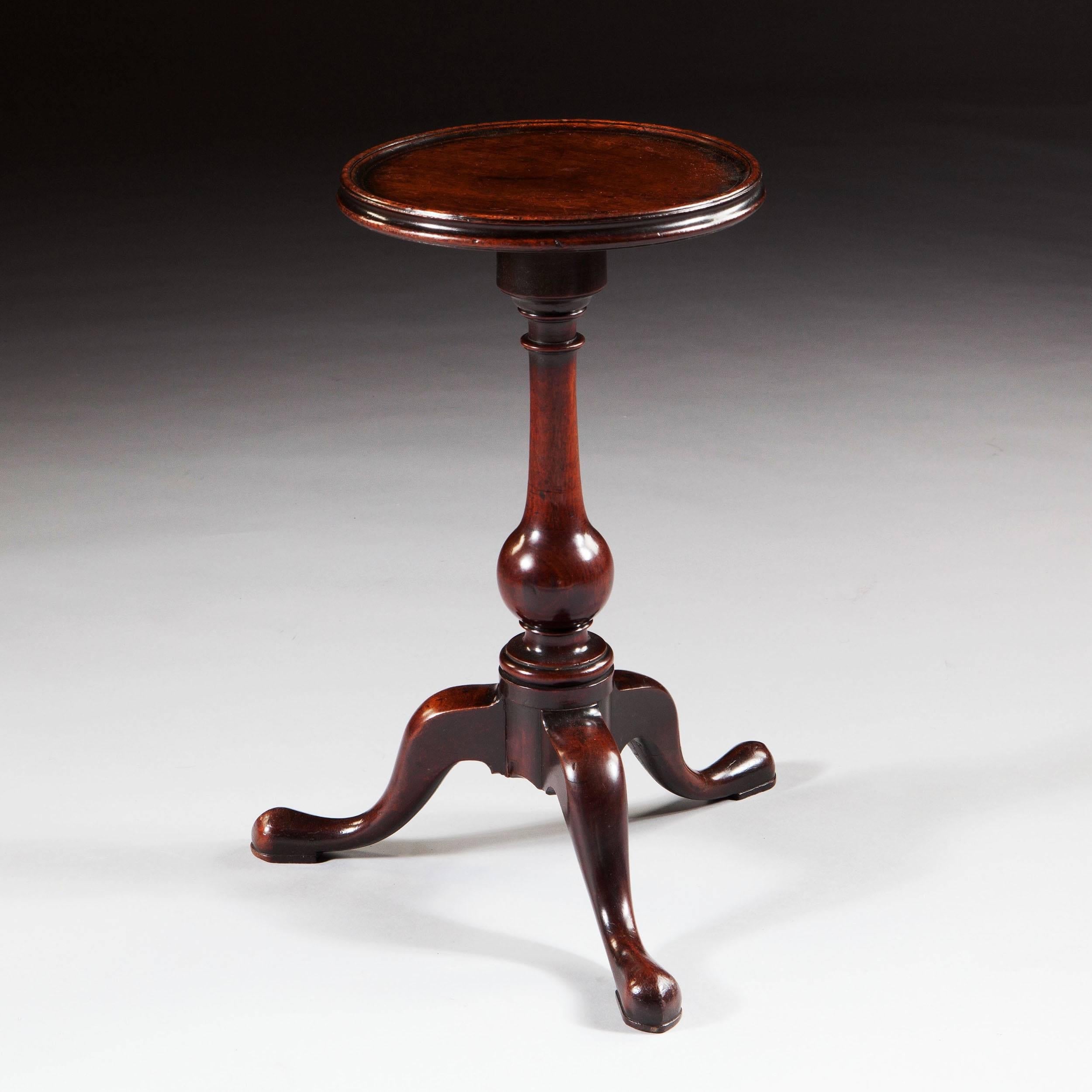 England, circa 1740.

A George II mahogany tripod candle stand, the circular top with a moulded border on a baluster turned column and three down swept cabriole legs with pad feet.

Measures: Height 20