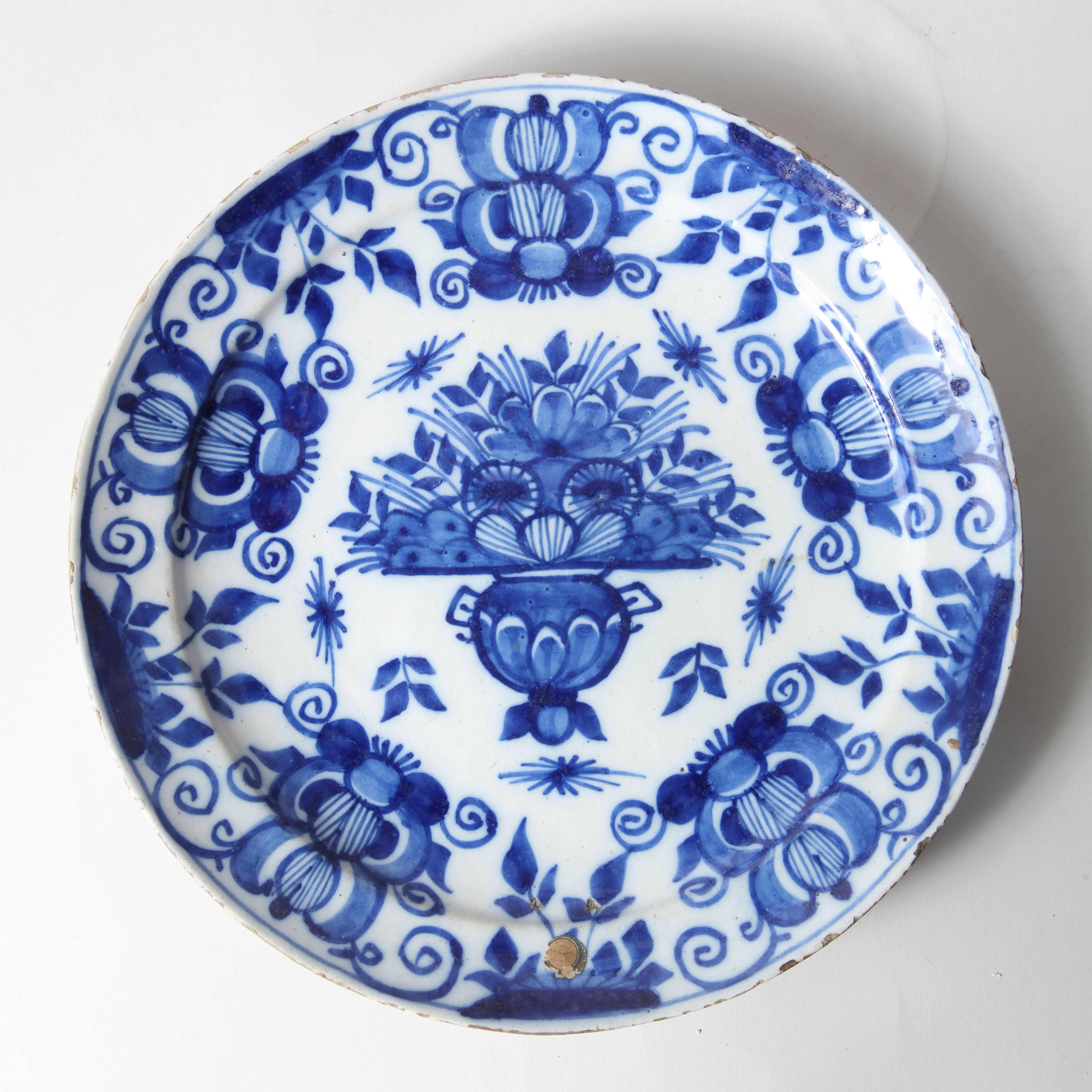 A rare pair of blue and white early 18th century Delft plates, decorated with a vase of flowers at the centre with a border of stylised pomegranates. Having unusual domed shaped backs and bearing old collection labels.

Low Countries, circa