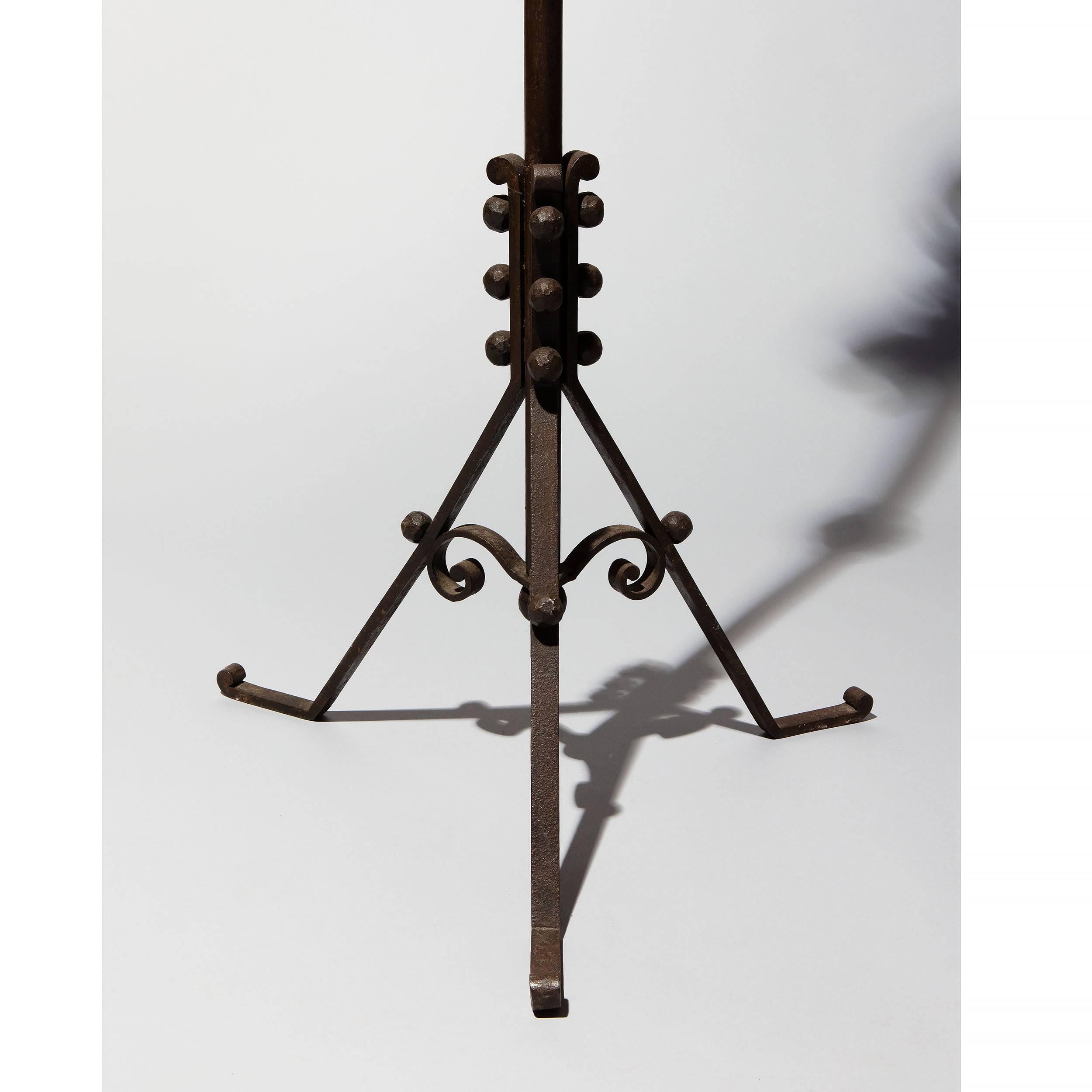 A Mid-Century wrought iron standard lamp with an elaborate scroll arm supported from the vertical upright with Classic Raymond Subes ornamental metal work. The shaft with three central discs of varied circumference and raised on three legs with