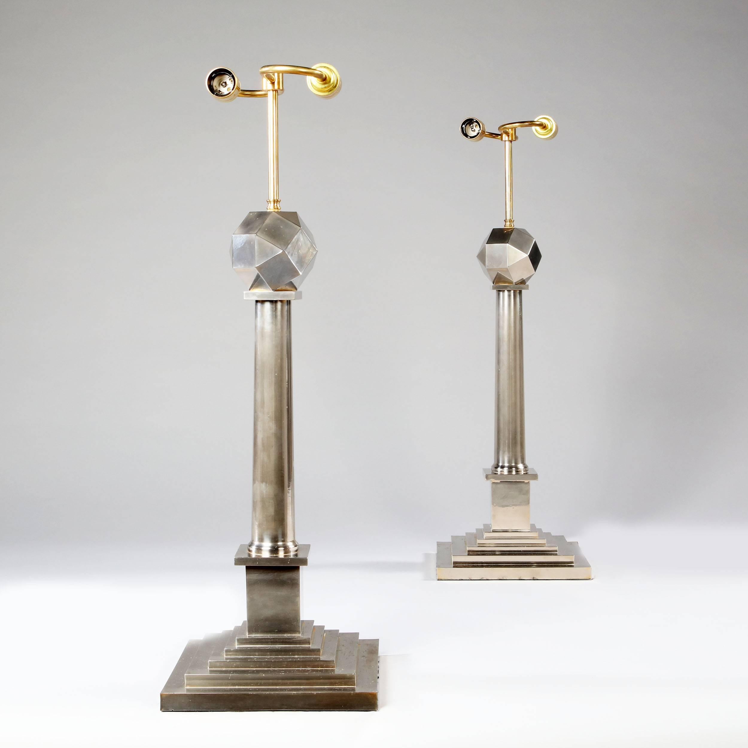 A pair of unusual Mid-Century column lamps in silver nickel, the stems are supported on exaggeratedly stepped plinths and are surmounted by overscale multi facetted spheres, France, circa 1950 (now wired for electricity).

Possibly Maison