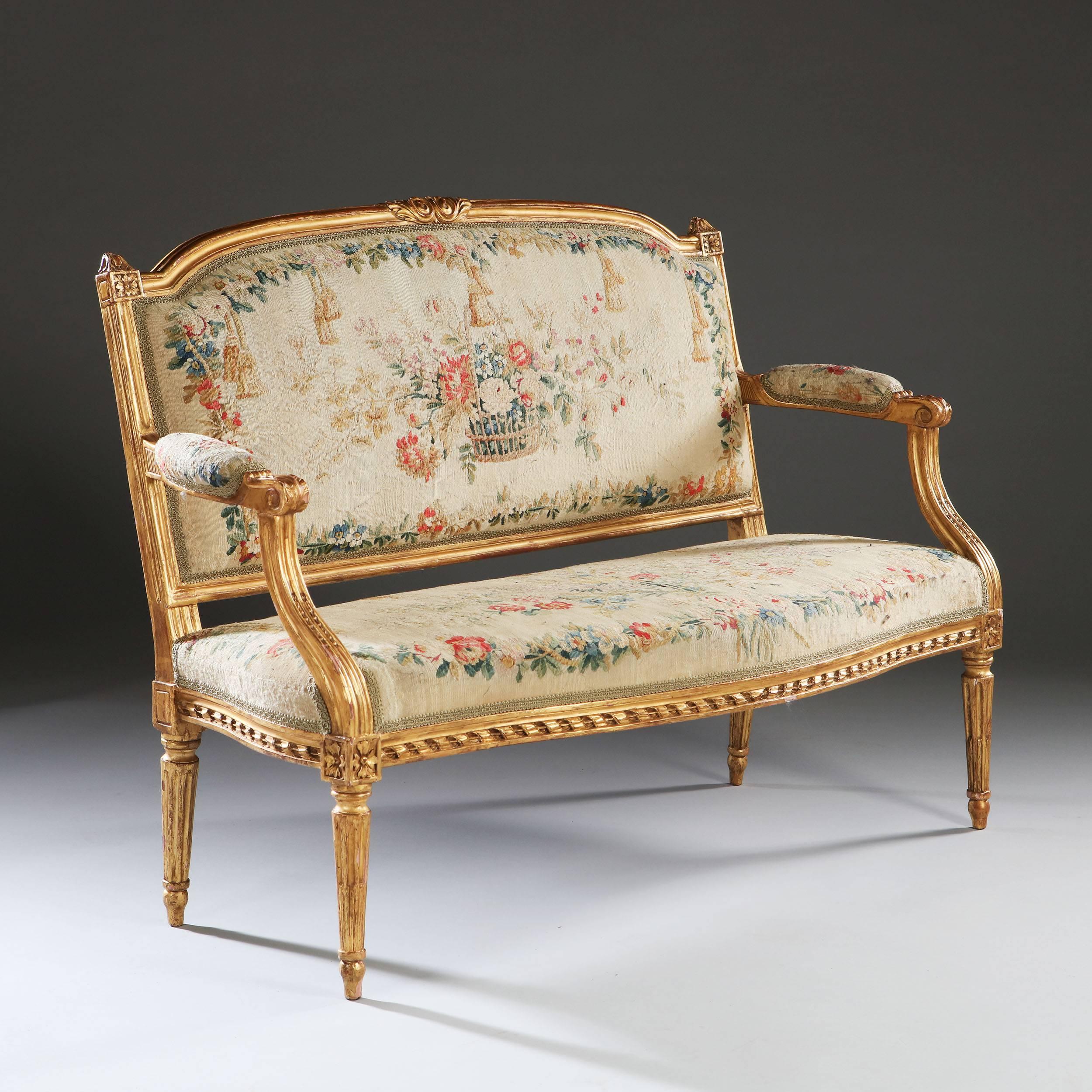A very fine pair of late 18th century Louis XVI neoclassical marquise retaining their original petit point needlework upholstery. The frames with neoclassical carved details, the shaped back with outswept arms, the bowed front apron with overlapping