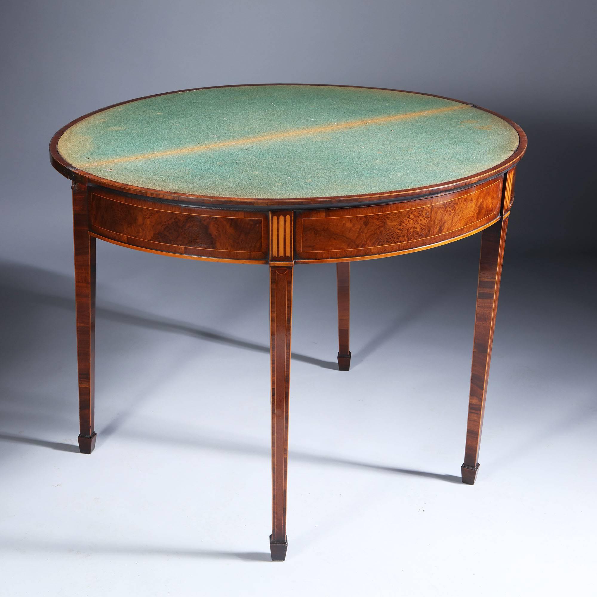 A fine quality George III inlaid mahogany demilune card table. The fold over top inlaid with a satinwood fan. The frieze has stringing around panels of amboyna and marquetry fluting at the top of the legs. The table is supported on square tapering