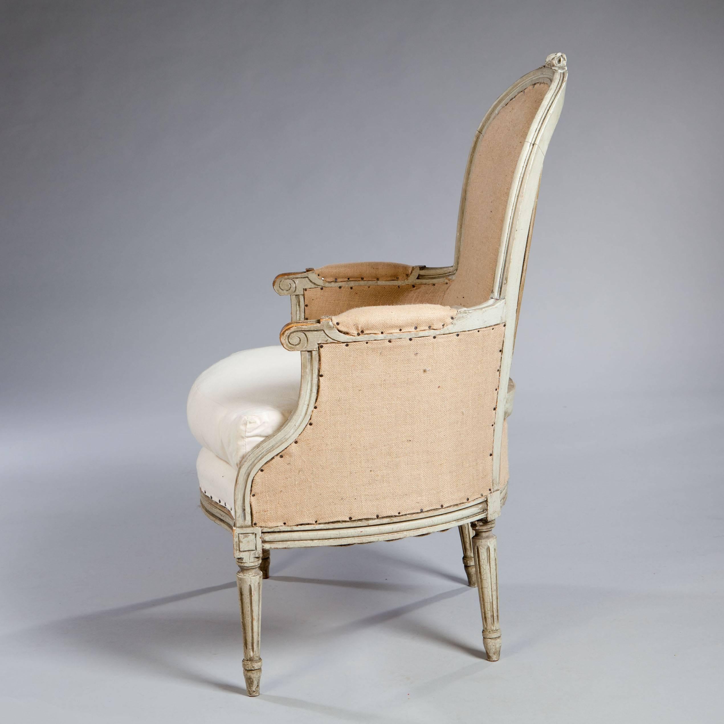 A charming pair of 19th century French antique neo classical bergere armchairs, the shaped backs offering generous support, raised on fluted tapering legs. Retaining the original paint finish.