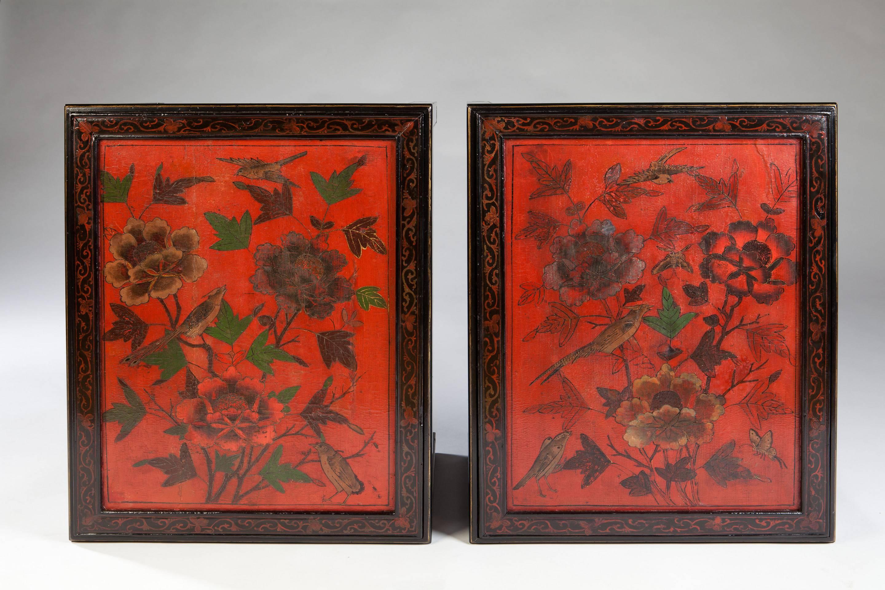 A decorative pair of mid 20th-century Chinese export black and red lacquer side tables. The black lacquer frames inset with vibrant red lacquer panels decorated with birds amongst green foliage and flowers.