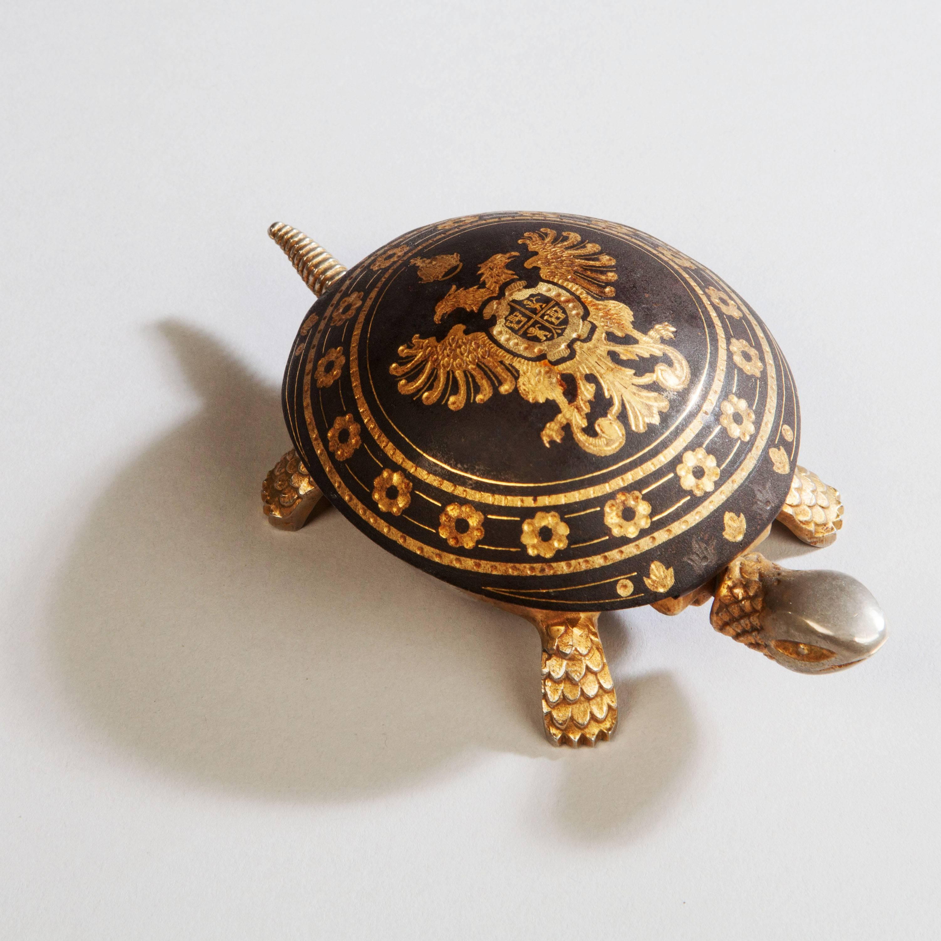 A fine 20th century table bell in the form of a tortoise, the damascened and gilt tortoiseshell with the Imperial Royal Coat of Arms of the Holy Roman Emperor. 

Pressing the head or tail triggers the wind up bell.