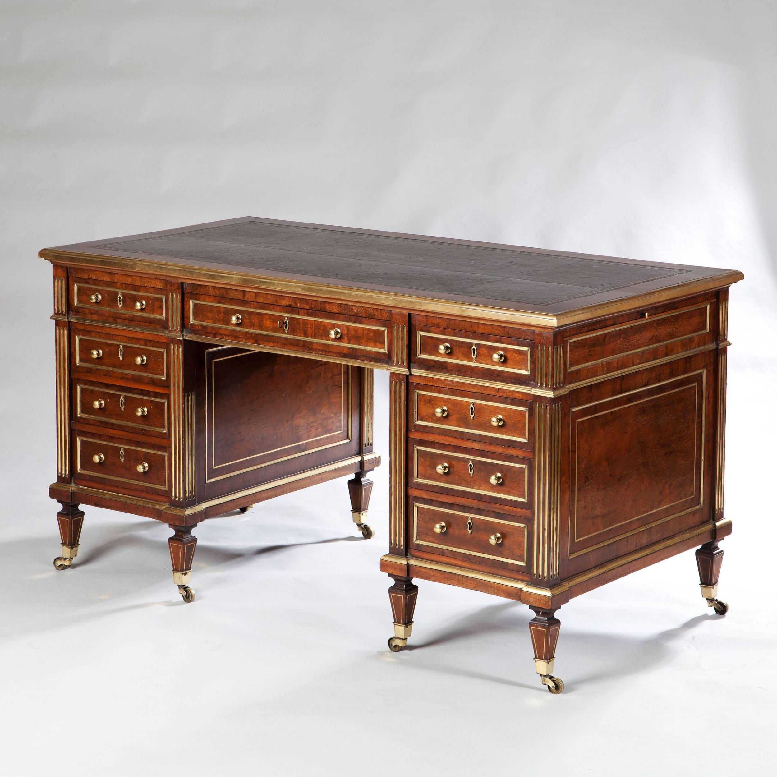 A very fine and good looking pedestal desk, the leather top with brass bound edges, above a bank of four drawers on each side with one central drawer, the back with dummy drawers. The whole raised on tapering legs on brass castors. The desk with two