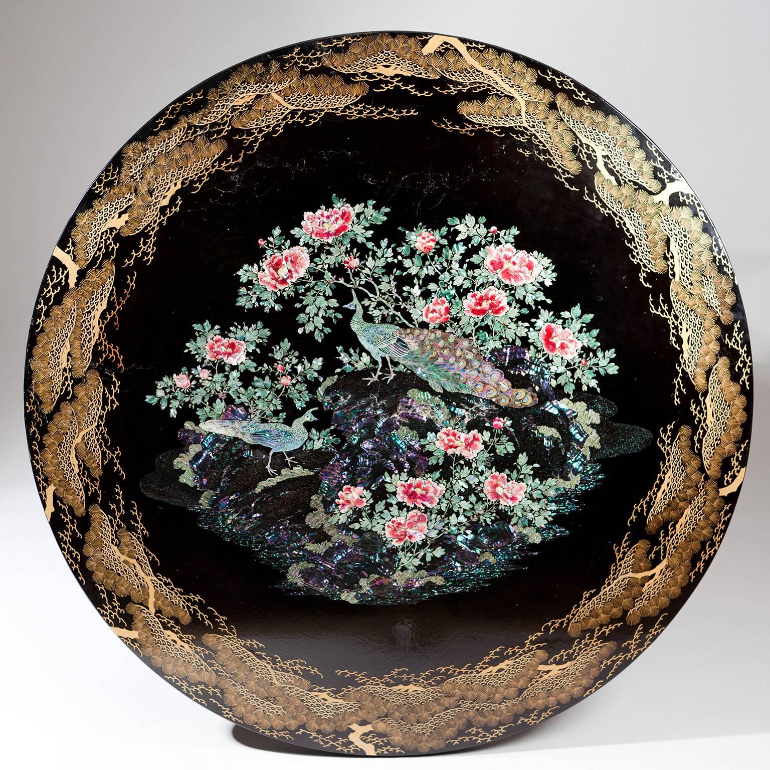 An exceptional mid-19th century Japanese lacquer center table, the top inlaid with mother-of-pearl and abalone shell marquetry of peacocks among peonies. 

The revolving drum top with single drawer in the frieze, raised on a column base supported