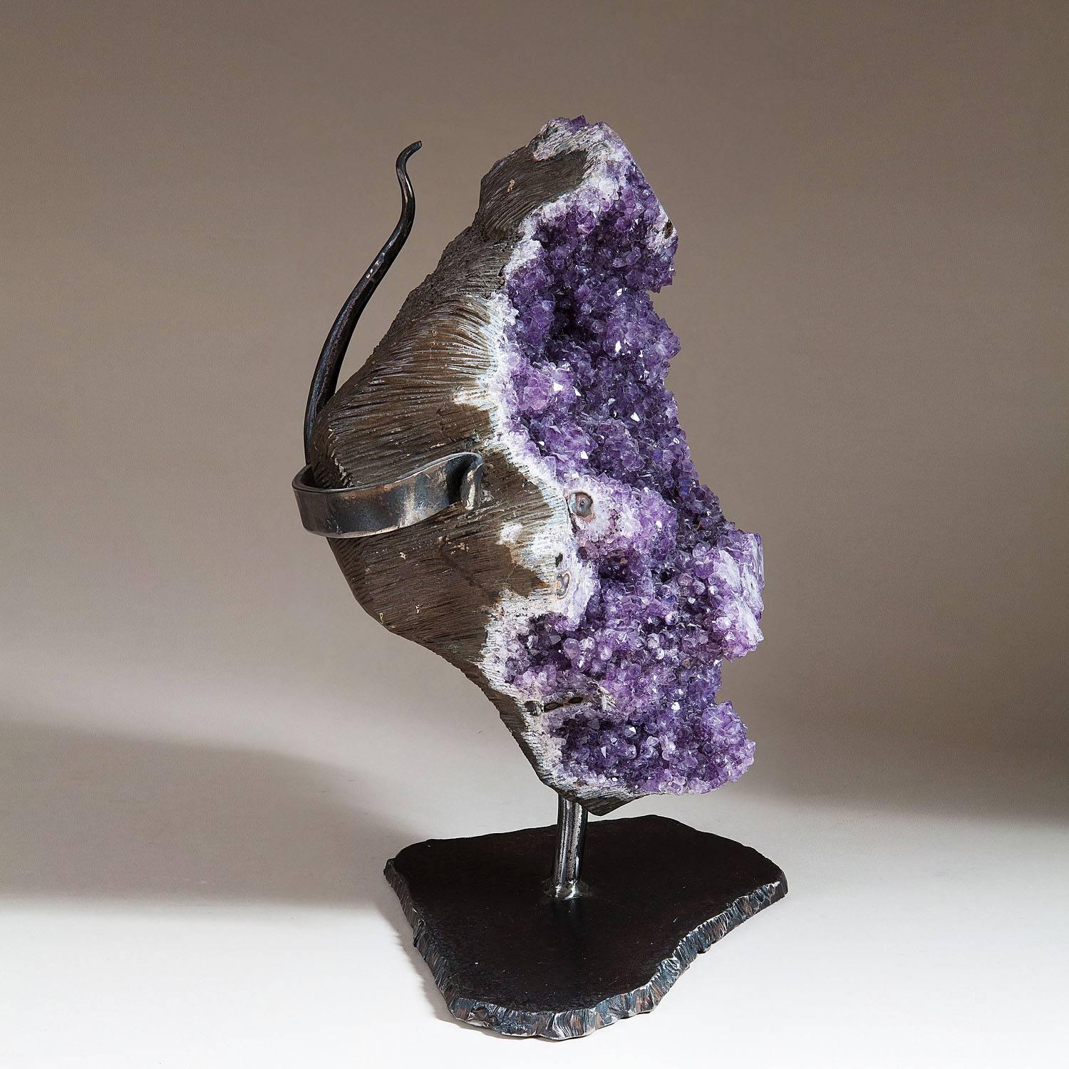 Brazil.

A substantial specimen of Brazilian amethyst mounted on a wrought iron base

including stand.
Measures: H 49.5cm. 
W 38cm.
D 24 cm.